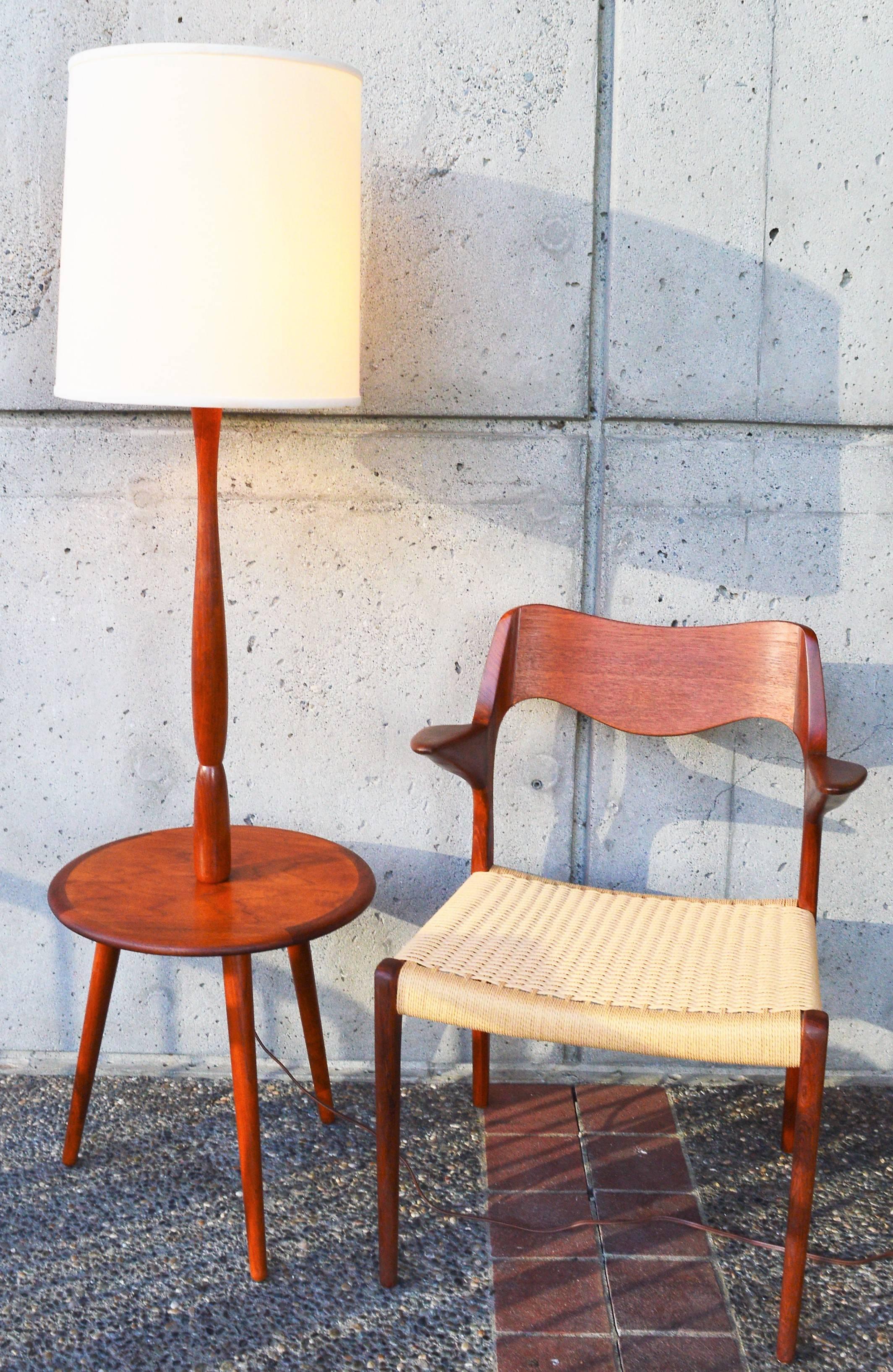 This super practical Danish Modern teak floor lamp has a lovely built in round table top so serves two purposes! 3 splayed tripod conical legs, a sculptural teak main stem, and a classic cream fabric barrel shade complete the look. In awesome