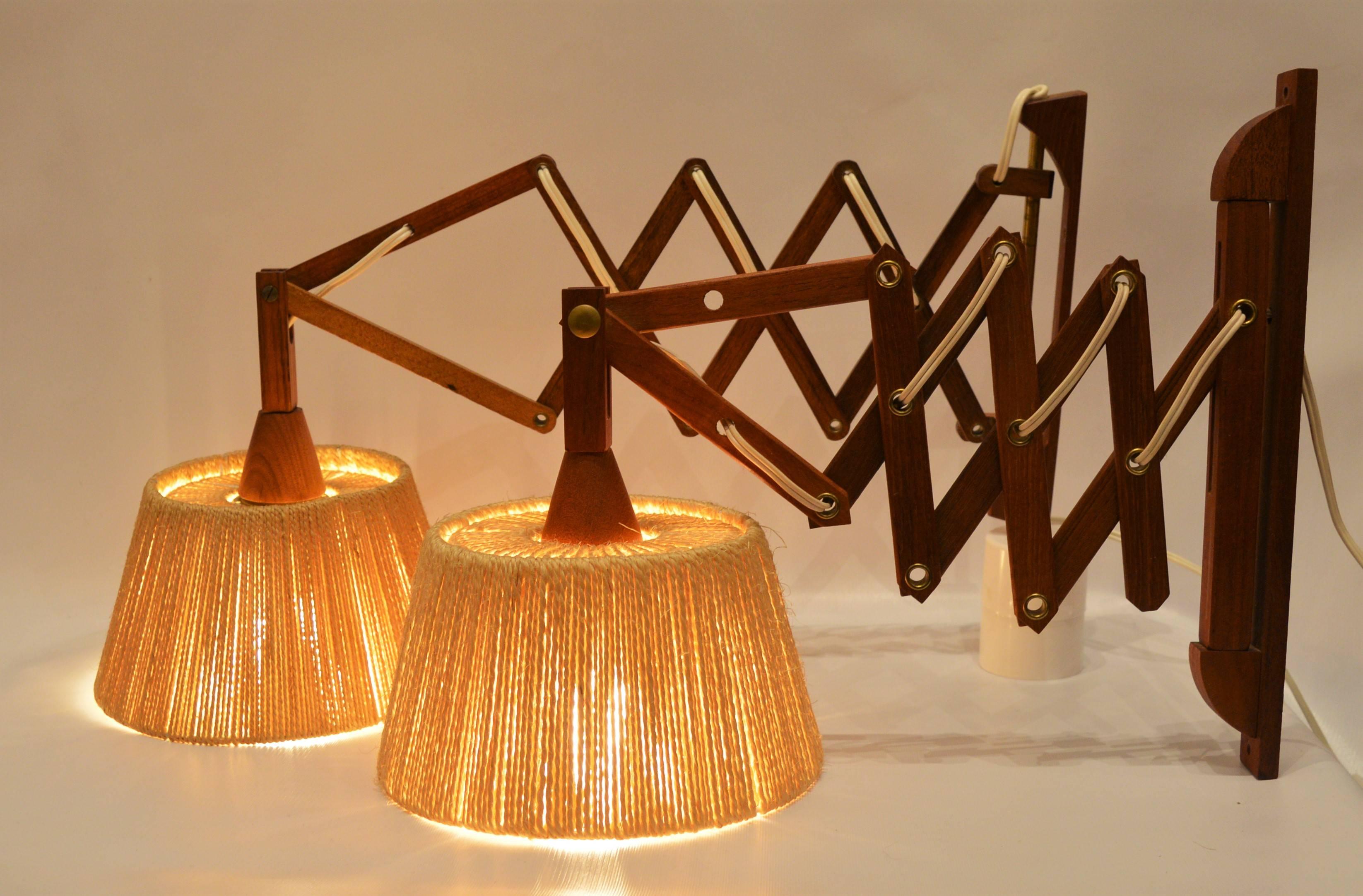 These lovely Danish Modern teak and jute Scandinavian scissor or accordion wall lamps are super practical as they take no table space and are made in the style of Fog & Mørup.  The wall mount lamps screw to the wall and simply plug into an