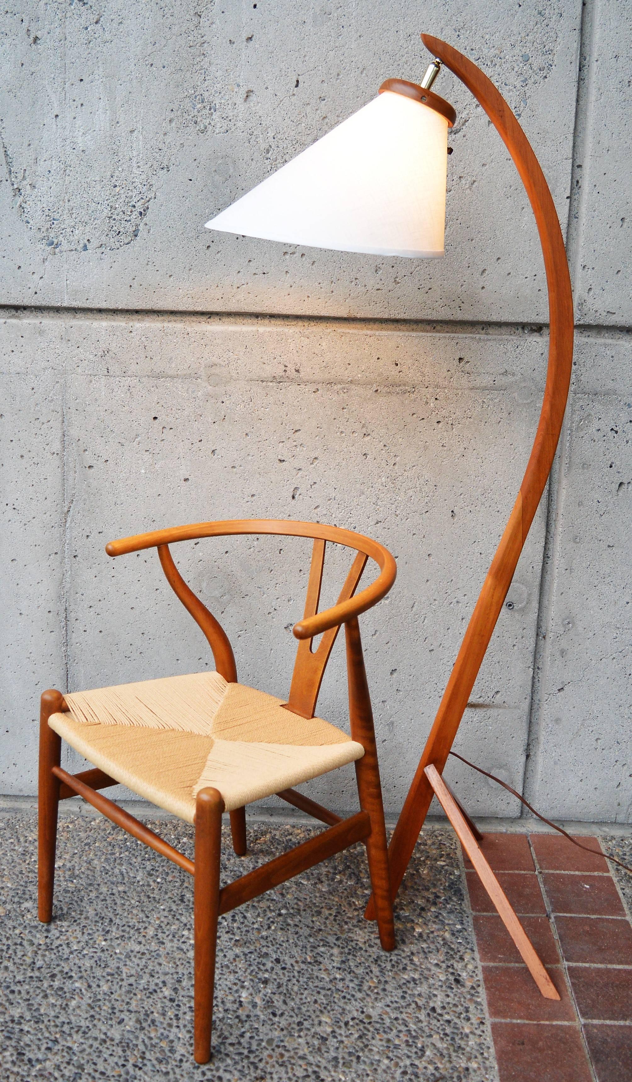 This hot Danish modern teak tall and graceful arc lamp has a great tripod base and a crisp white new custom bonnet shade. The brass neck hardware allows you to angle the shade as needed, and the light switch protrudes out the back of the shade for