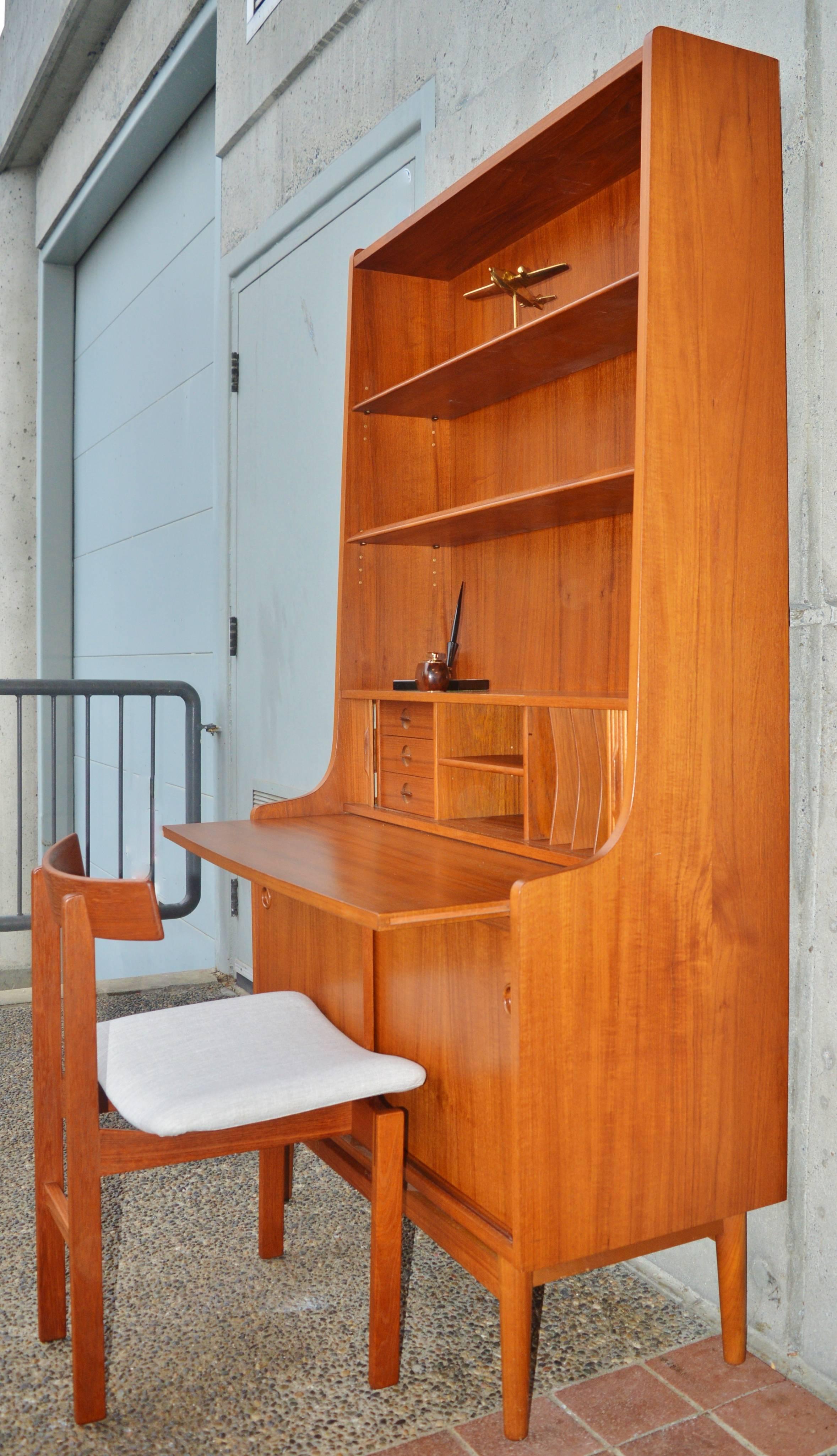 This stellar quality all hardwood constructed teak secretary / bookcase by acclaimed Danish designer, Borge Mogensen, is just gorgeous! Featuring a central tambour door that opens to reveal 3 tiny drawers with crossed circle pulls and various pigeon
