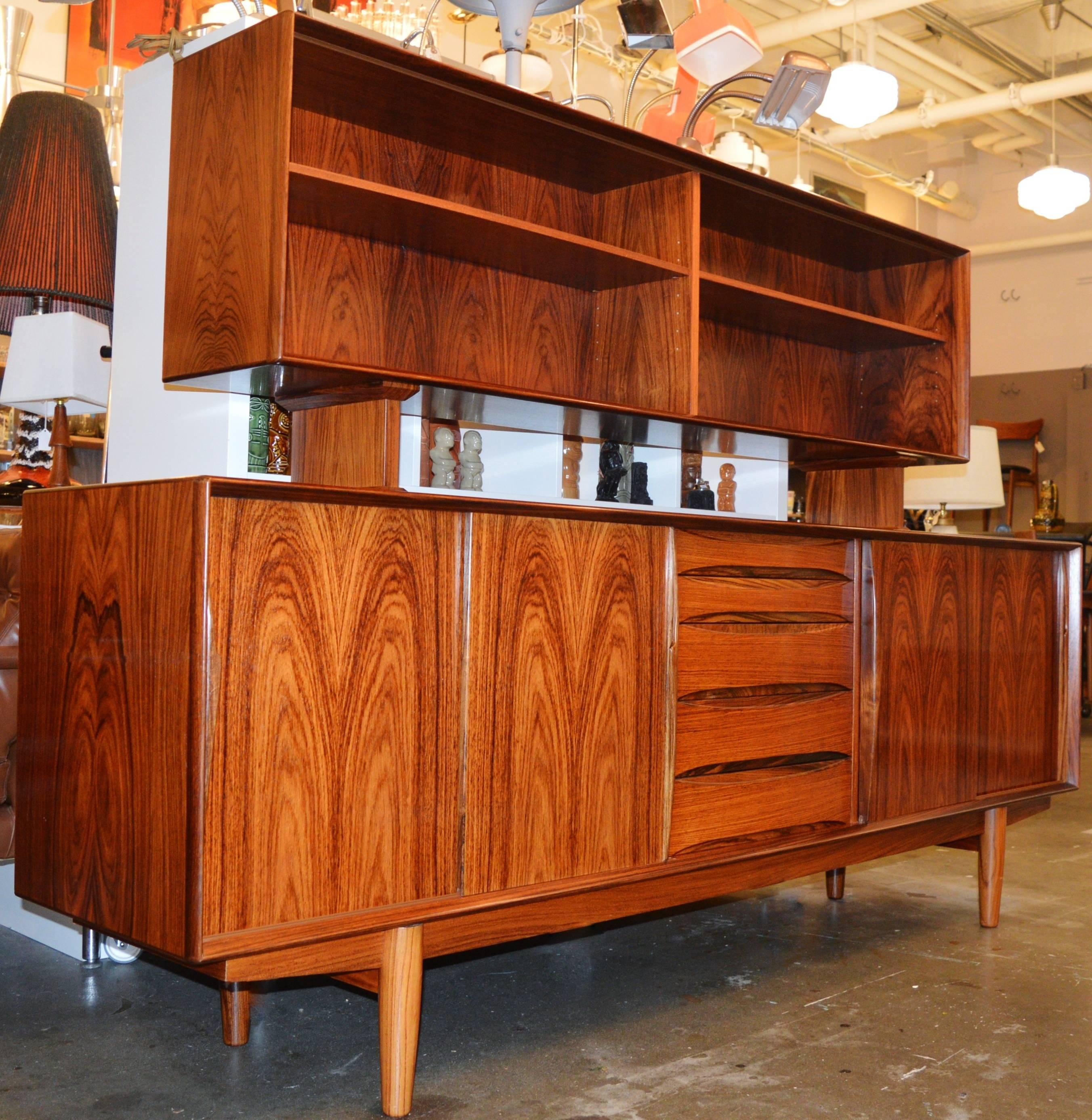 This absolutely stunning Danish modern rosewood buffet and hutch were made by Skovby Mobelfabrik in the style of Arne Vodder and are in excellent original condition. The lower buffet/credenza features four sliding doors with bookmatched grain and