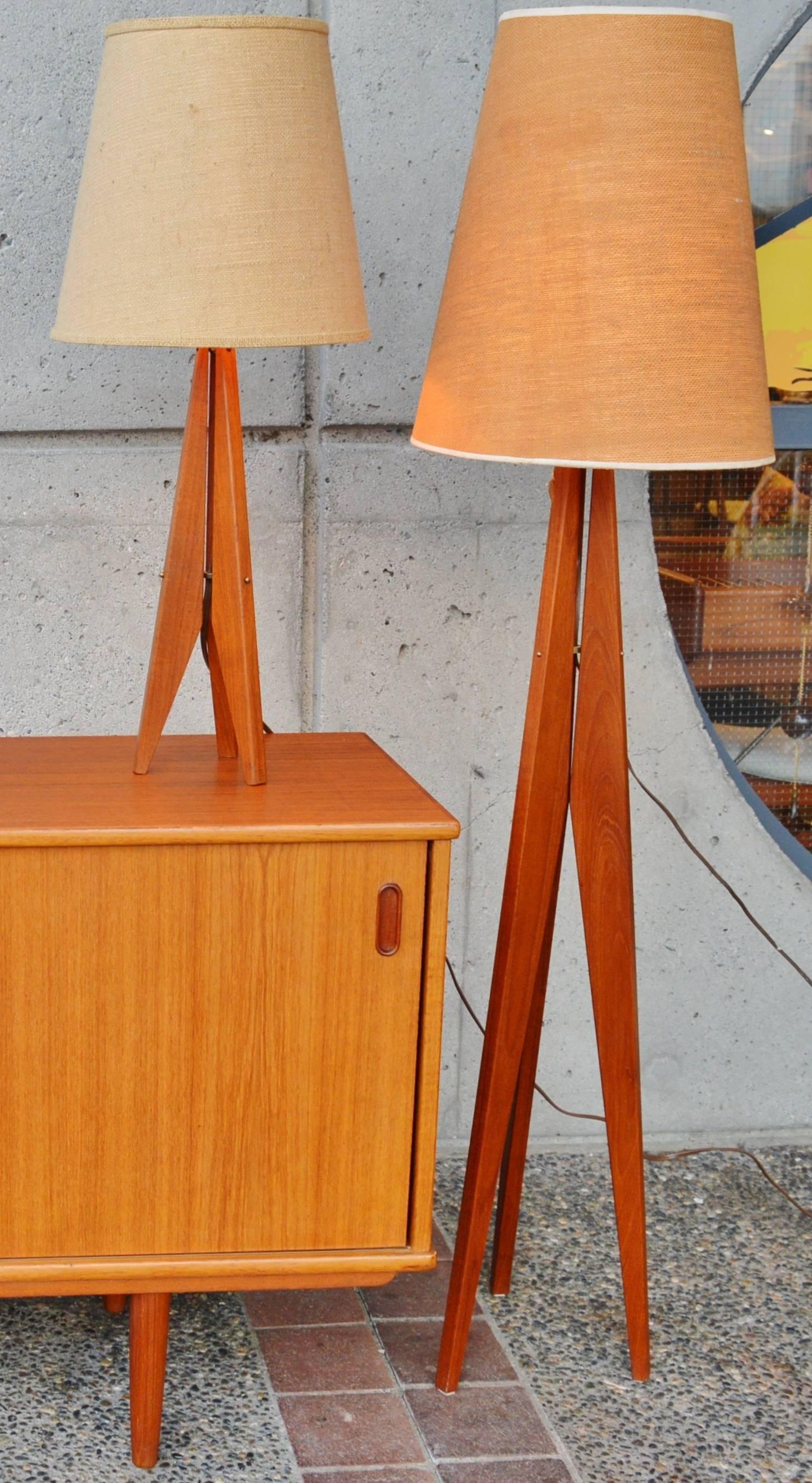These stellar Danish Modern teak tripod lamps are iconic and minimalistic. Each is made with 3 solid teak legs that taper at the top, flare in the middle, and then taper again to the ends with brass hardware to connect them. In excellent condition.