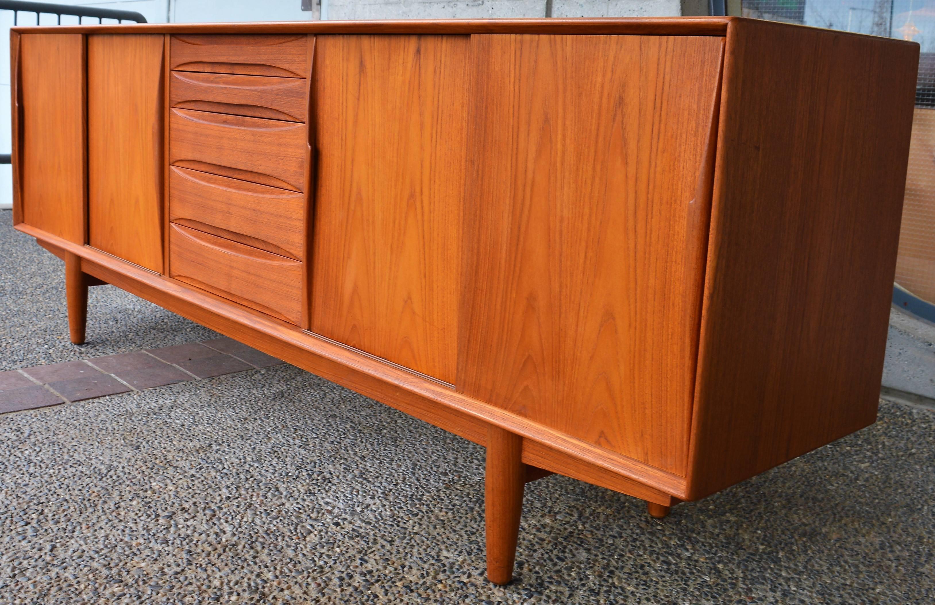 This impeccable Danish Modern teak buffet is exquisite throughout and was inspired by Arne Vodder for Dyrlund. Featuring a center bank of bow-tie shaped drawers, with all hardwood construction and dovetail joins (the top two are slimmer and felt