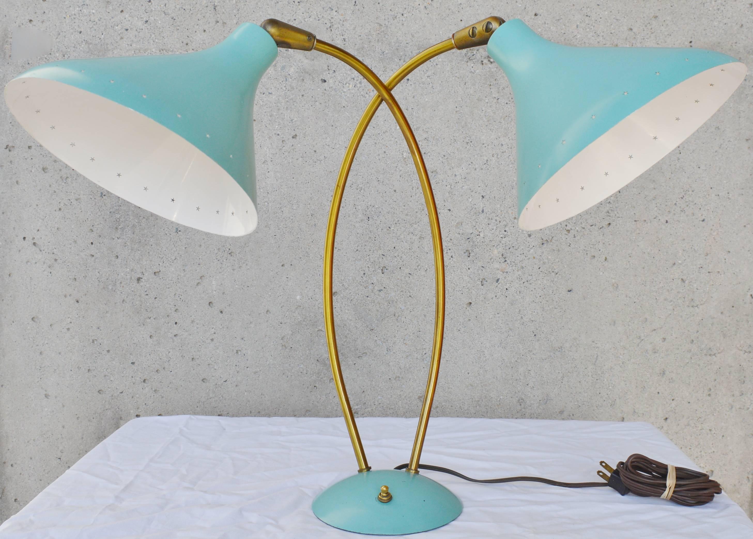This stunning vintage Italian sky blue metal and brass lamp is certainly in the style of Stilnovo, with its bell shaped metal shades and Atomic Era styling. Note the star-shaped holes that circle the shades, the cross necked brass stems, and the