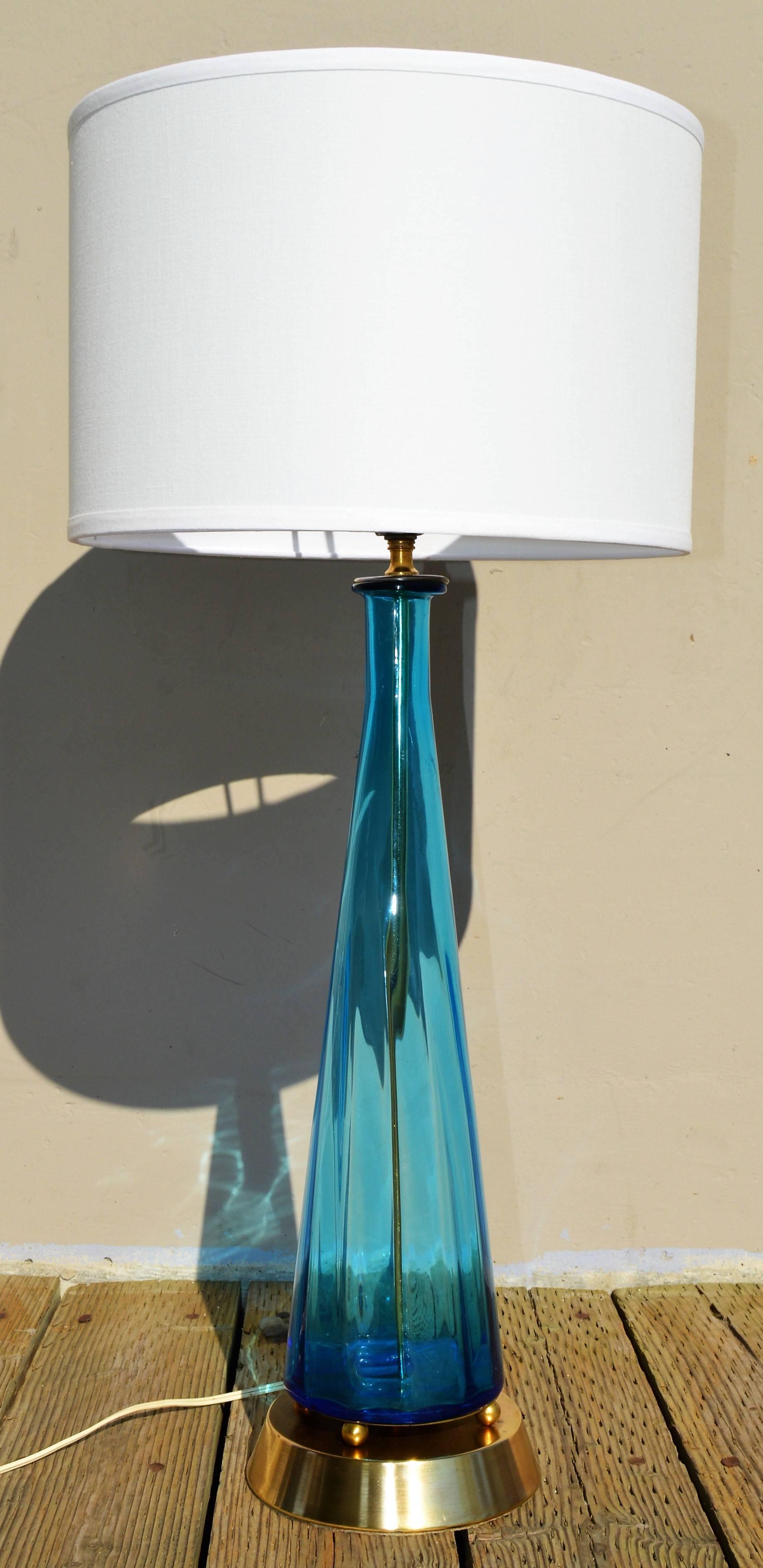 This stunning 1950s Murano Italian glass lamp is the most delicious shade of blue. The glass floats atop four brass balls on a flared brass base. Not original, but a perfect pairing with the brass claw foot blue glass finial. Featuring a new crisp