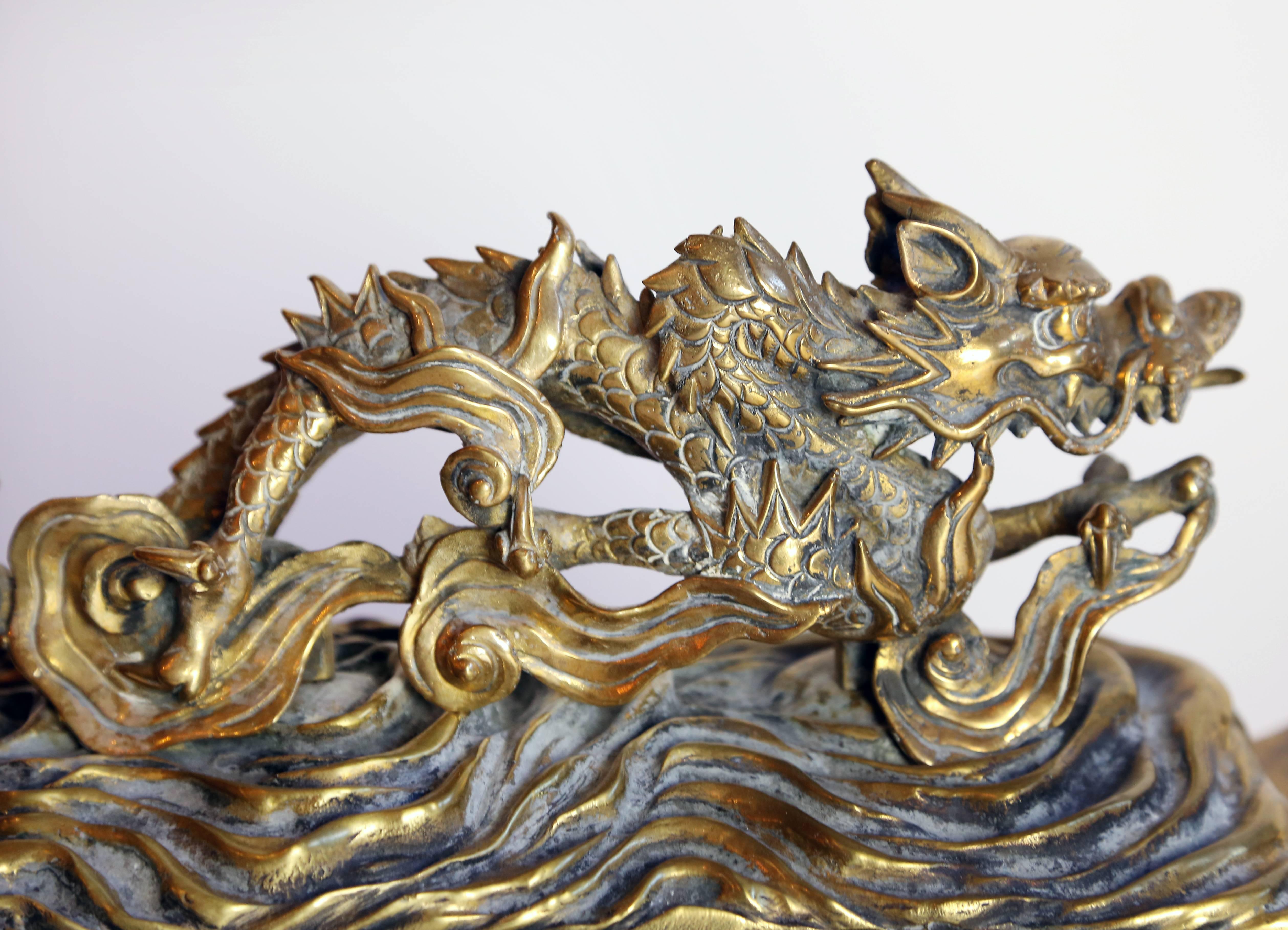 Fanciful French dragon adorned chenets on a rectangular base with a pierced foliate footed base and a pagoda style detail at the top.