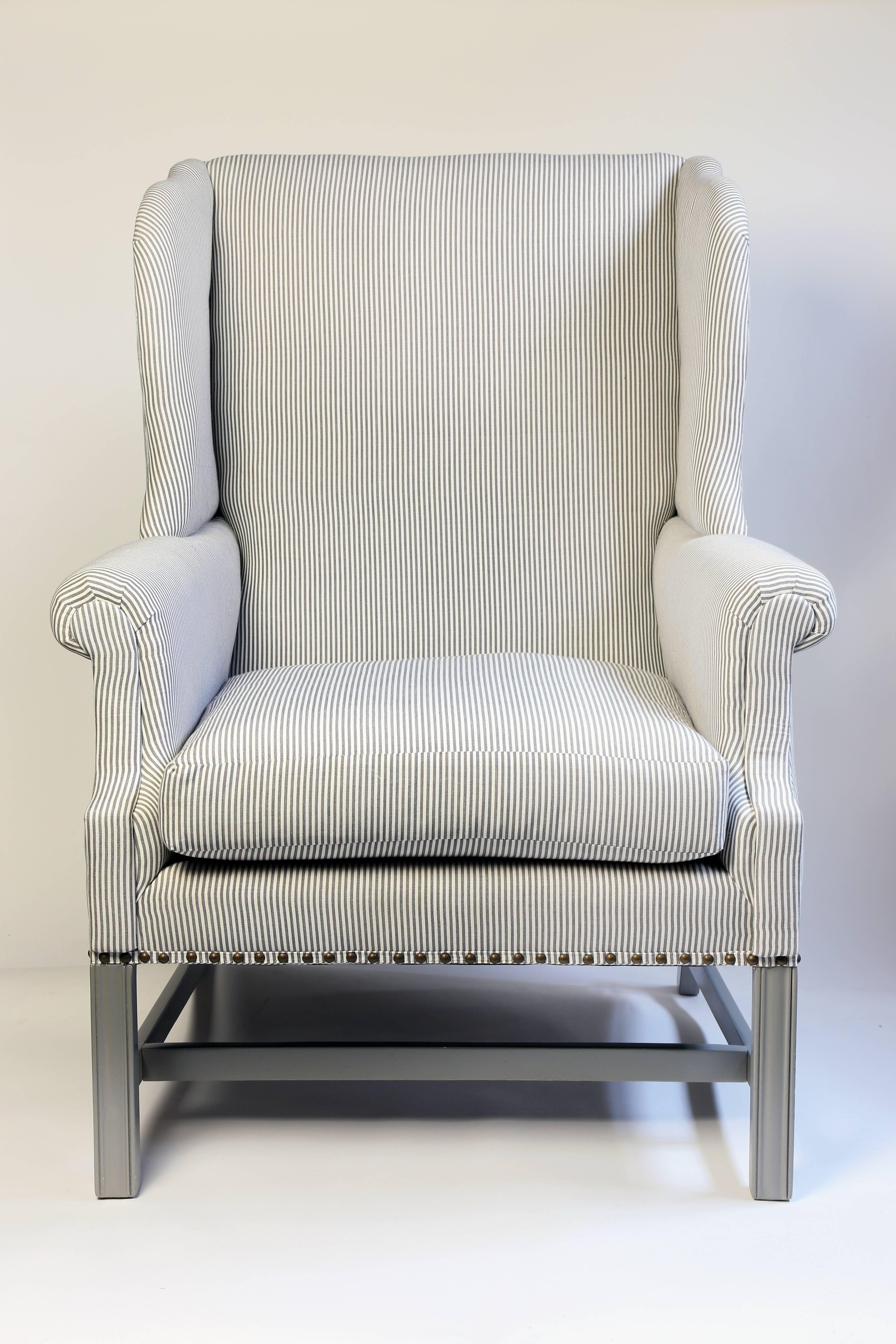 The newly upholstered wingback chairs have been upholstered in a cotton ticking stripe by Romo with a self tape and nailhead detail. The legs and stretchers have been painted to match the stripe.