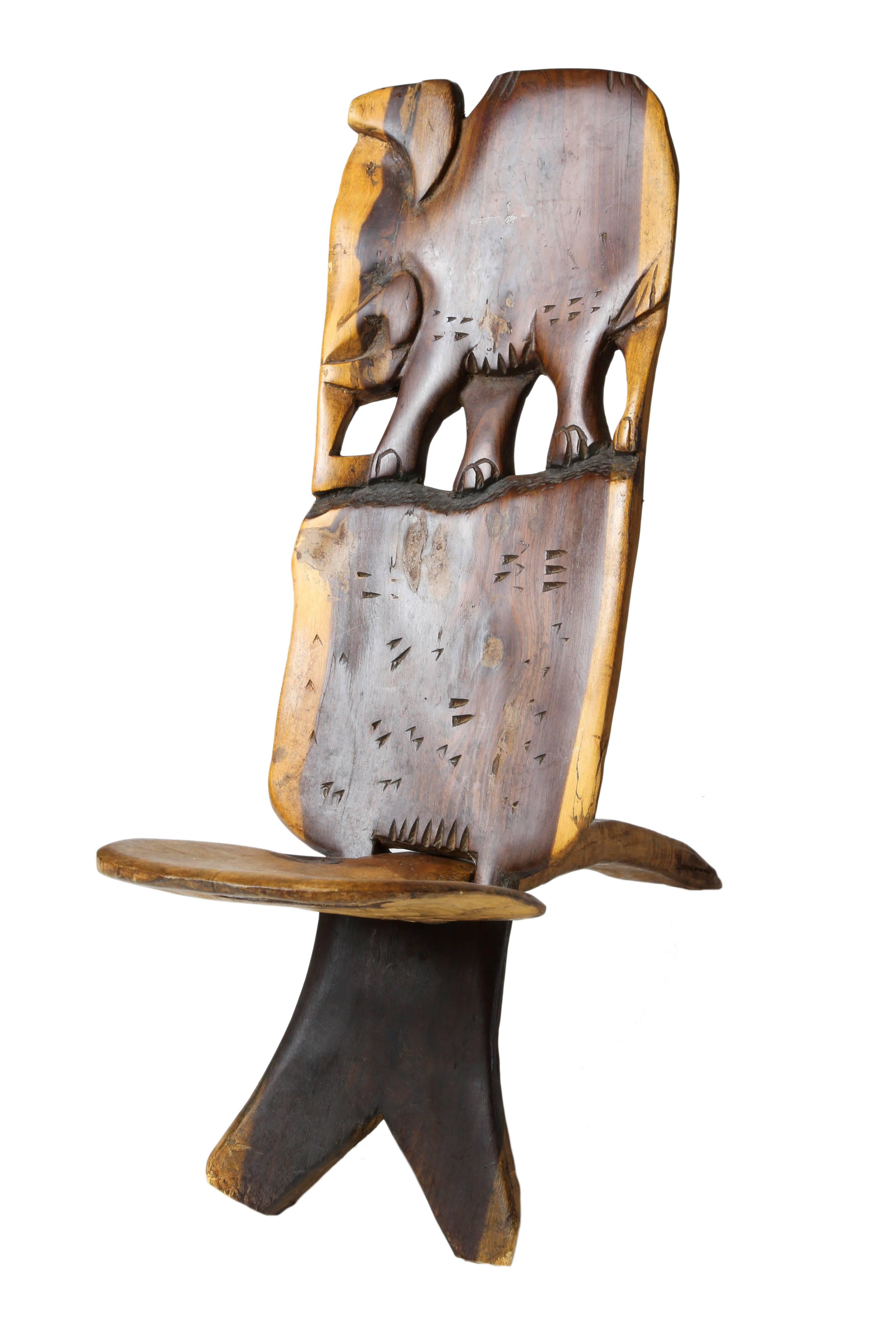 African two part small chair with carved elephant at the upper back, the seat fits into a pierced slot at center of the back board.