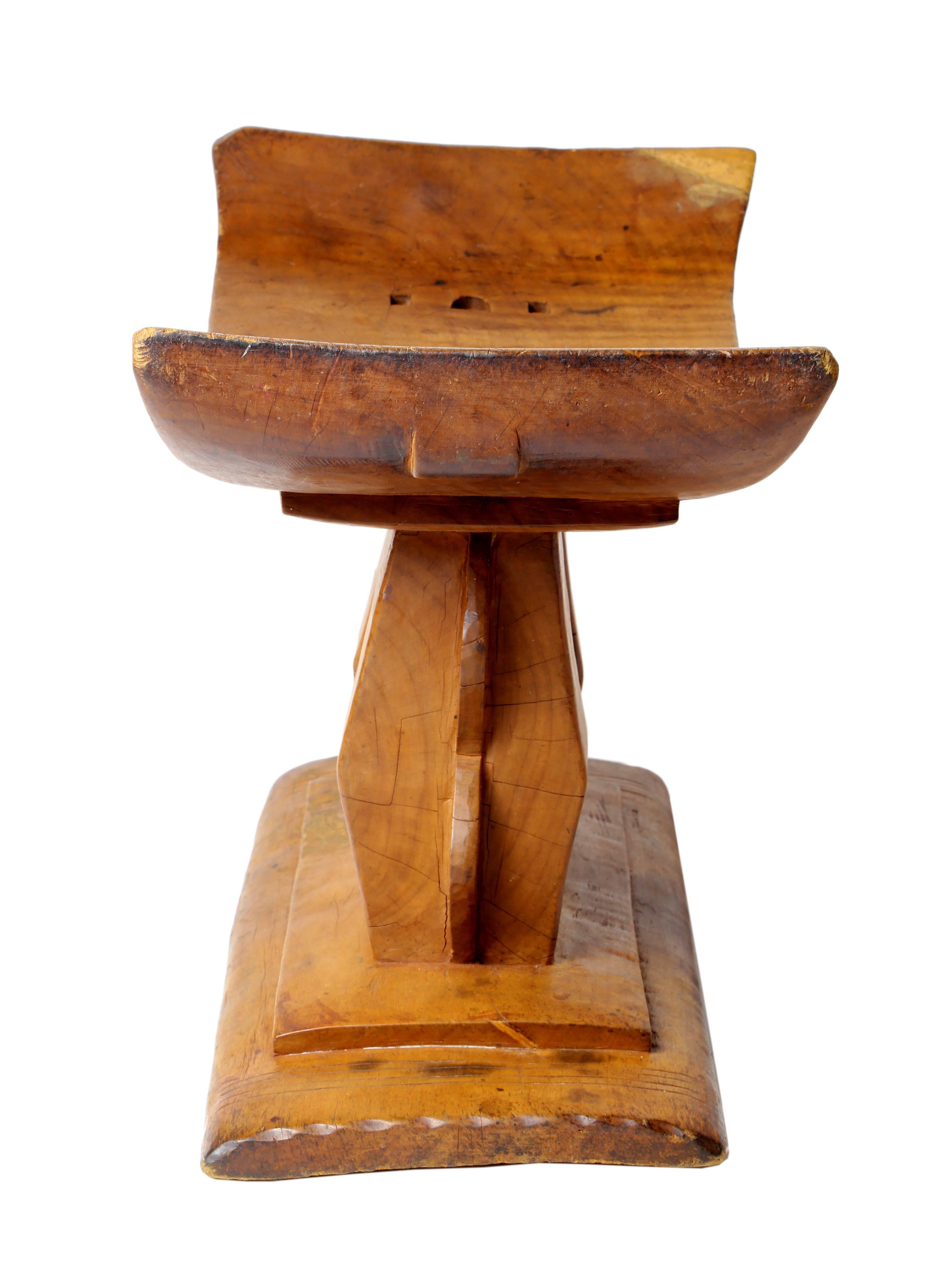 Carved from a single piece of wood, the African Ashanti head rest, Ghana, 20th century, has a curved top raised on two short pedestals rising form a stepped base.