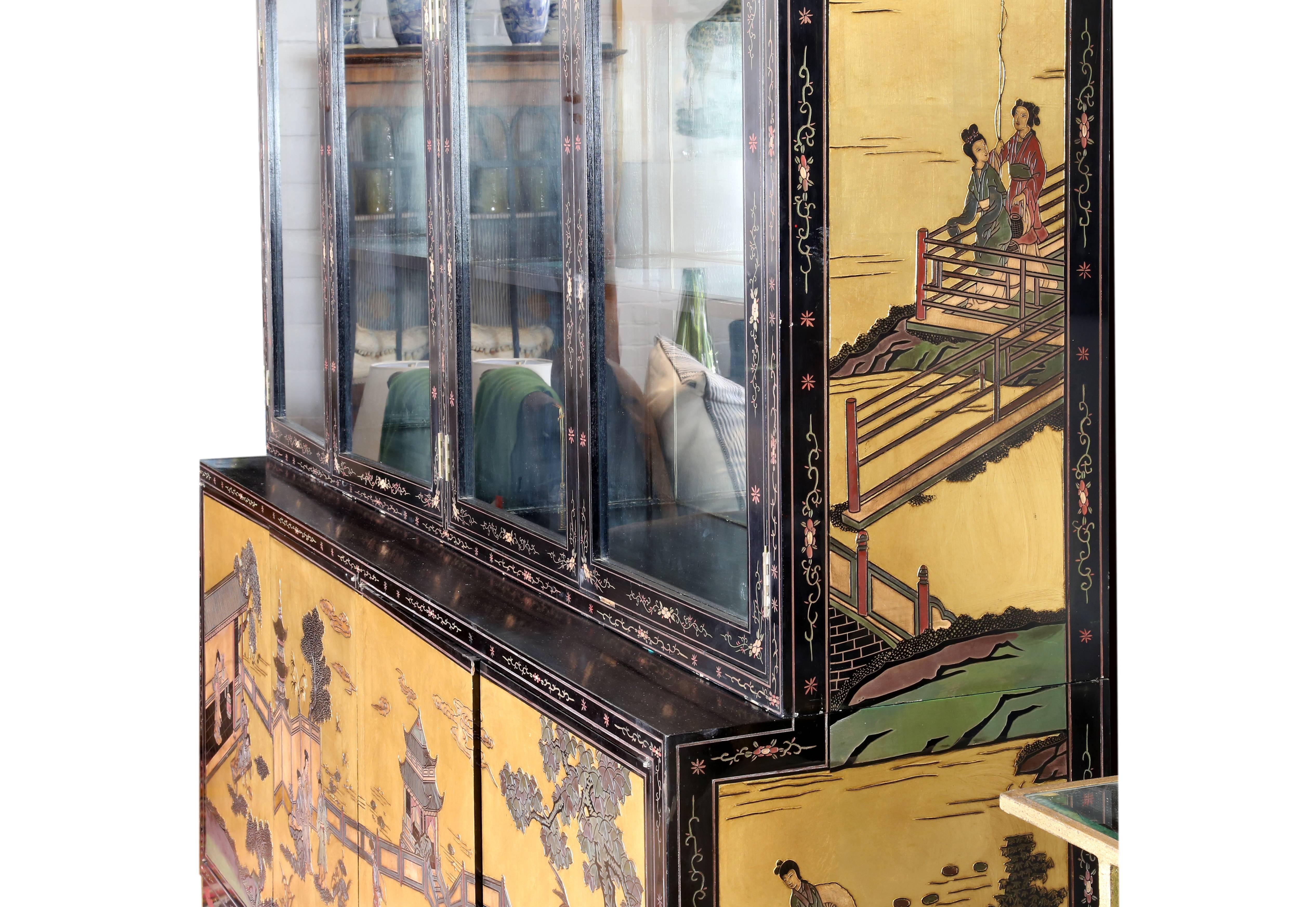 A black lacquer display cabinet commissioned in 1977-1978 with unique embellishments.
The finish is decorated with Coromandel door panels in gilt and polychrome depicting figural landscapes, the upper cabinet with four glazed doors opening to