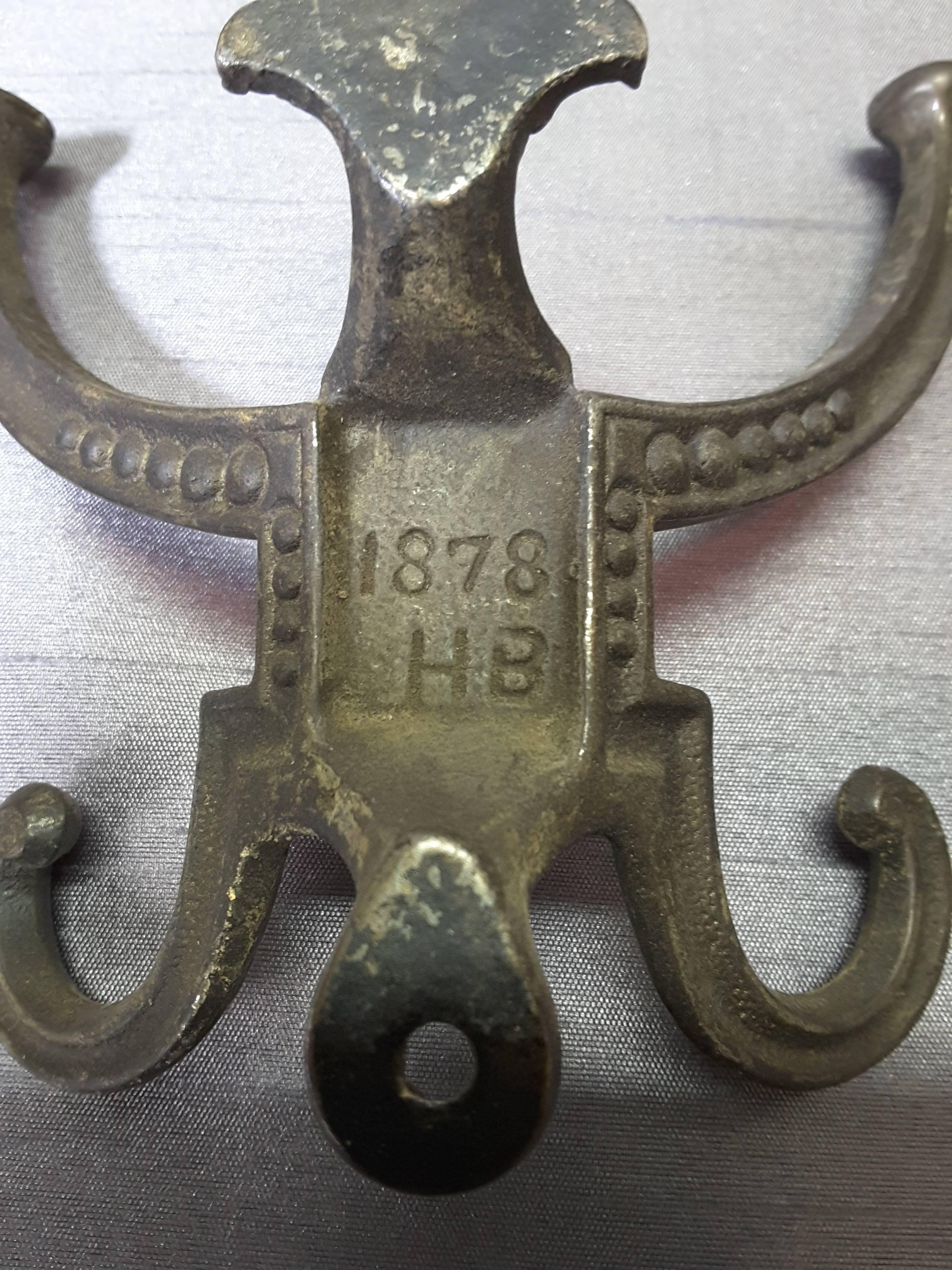 Pair of Victorian hallstand or coat stand hooks, dated 1878 and marked H.B. The hooks are four prongs on each hook, with upper and lower screw mount holes, made of cast iron, each hook is marked on the back centre. The hallstand hooks measure 5 3/4