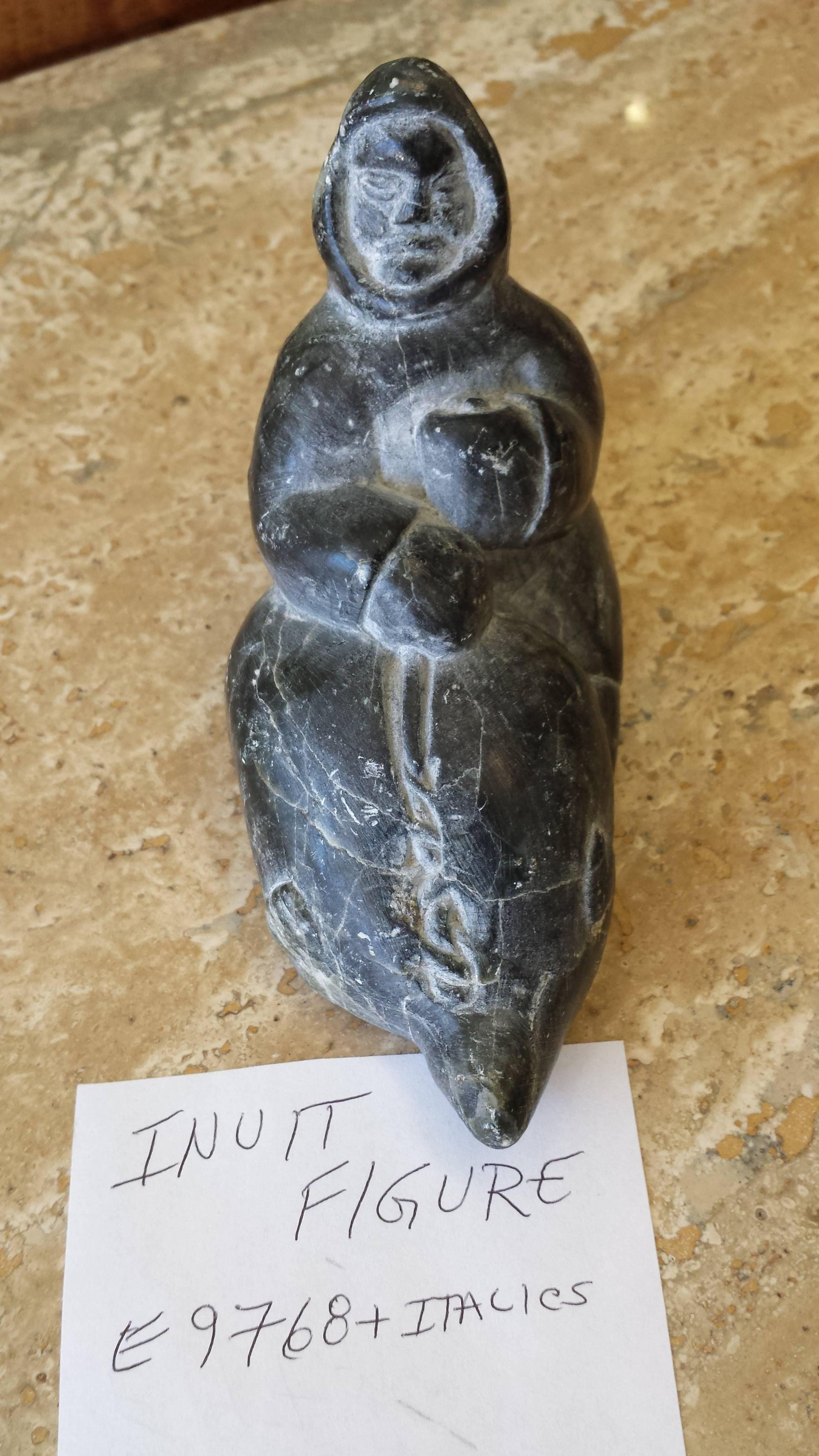 Soapstone Inuit Sculpture, Carving, Hunter Holding Seal, Signed in Syllabics & E Numbered for Carver I.D. The soapstone hunter measures 5"-inches long x 4"-inches high x 2 1/2"-inches wide, (Please see pics for bottom marks).