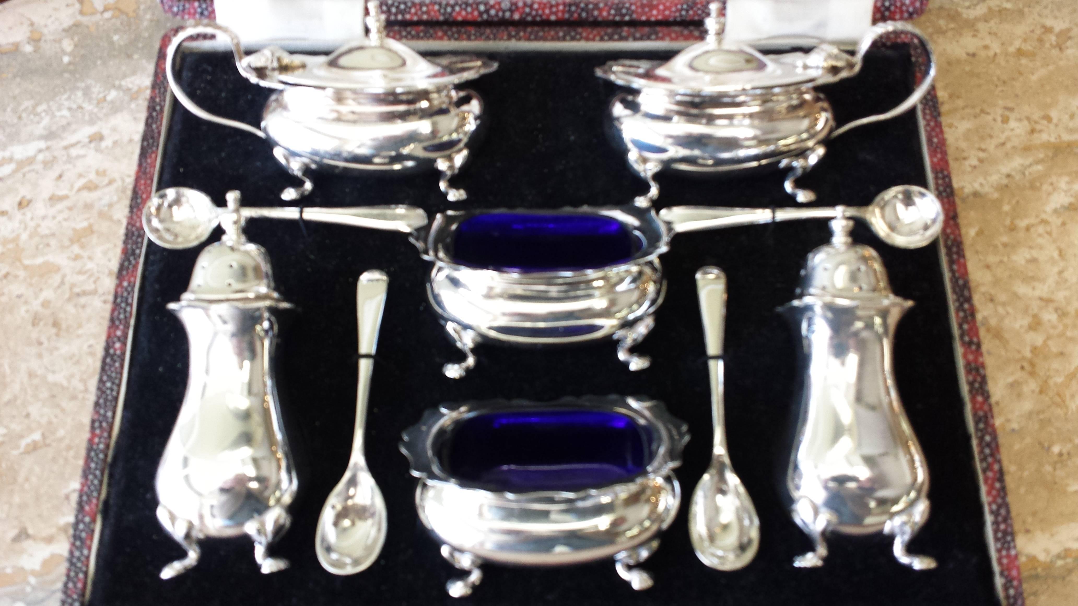 Walker & Hall, Sheffield, England, silver plate condiment set, circa 1930s, in a presentation box. The set has two pepper pots, two open salts, two condiment lidded pots and four spoons. The open salts and condiment pots are fitted with blue