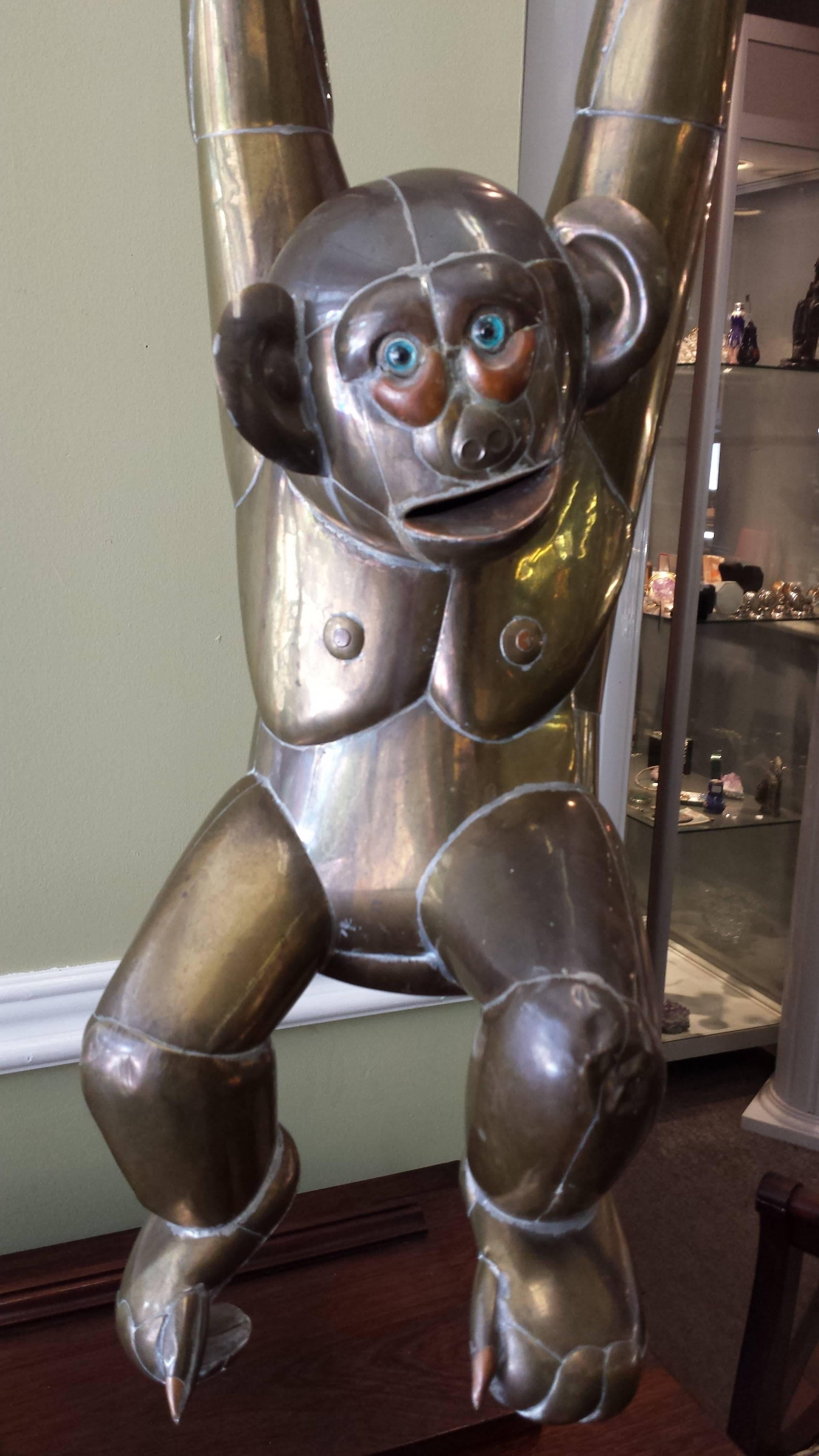 A large brass and copper monkey by Sergio Bustamante, 1960s, sculpted monkey hanging on a perch by Mexican artist Sergio Bustamante, nice large-scale and craftsmanship in its original mixed metals patina, on a swing perch. The monkey measures