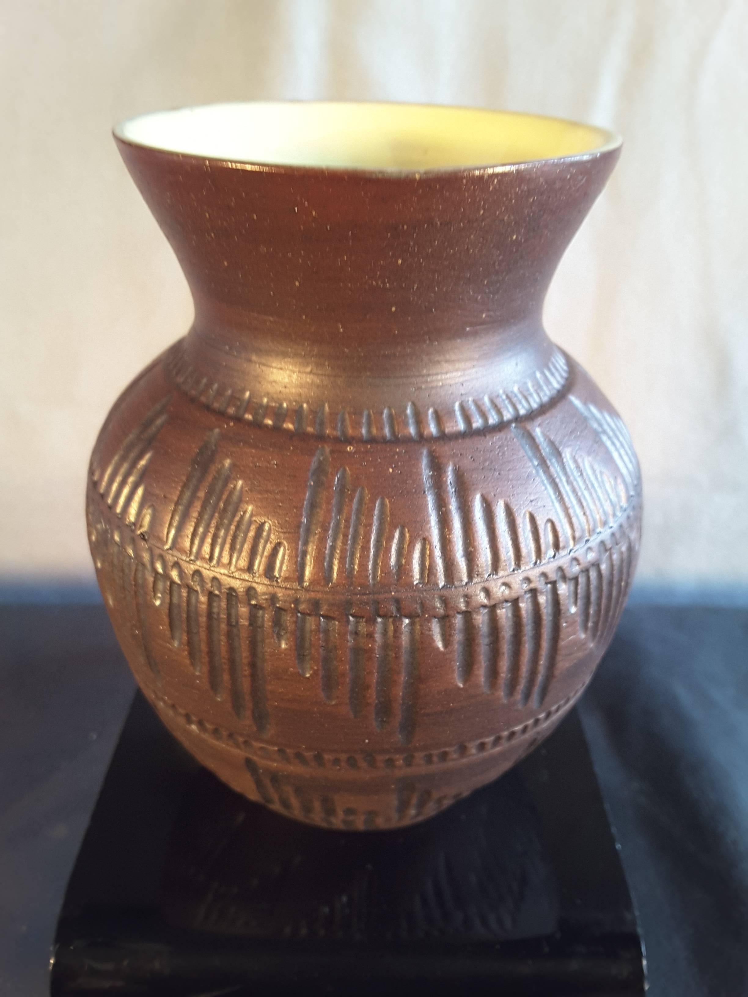 Eine Vase aus sechs Nationen indianischer Töpferware mit gelber Innenseite/brauner, eingeritzter Außenseite. Die Vase ist auf der Unterseite mit einer Adlerfedermarke und S.N. plus S.4. & S, unten gestempelt. Die Vase misst 4 3/4