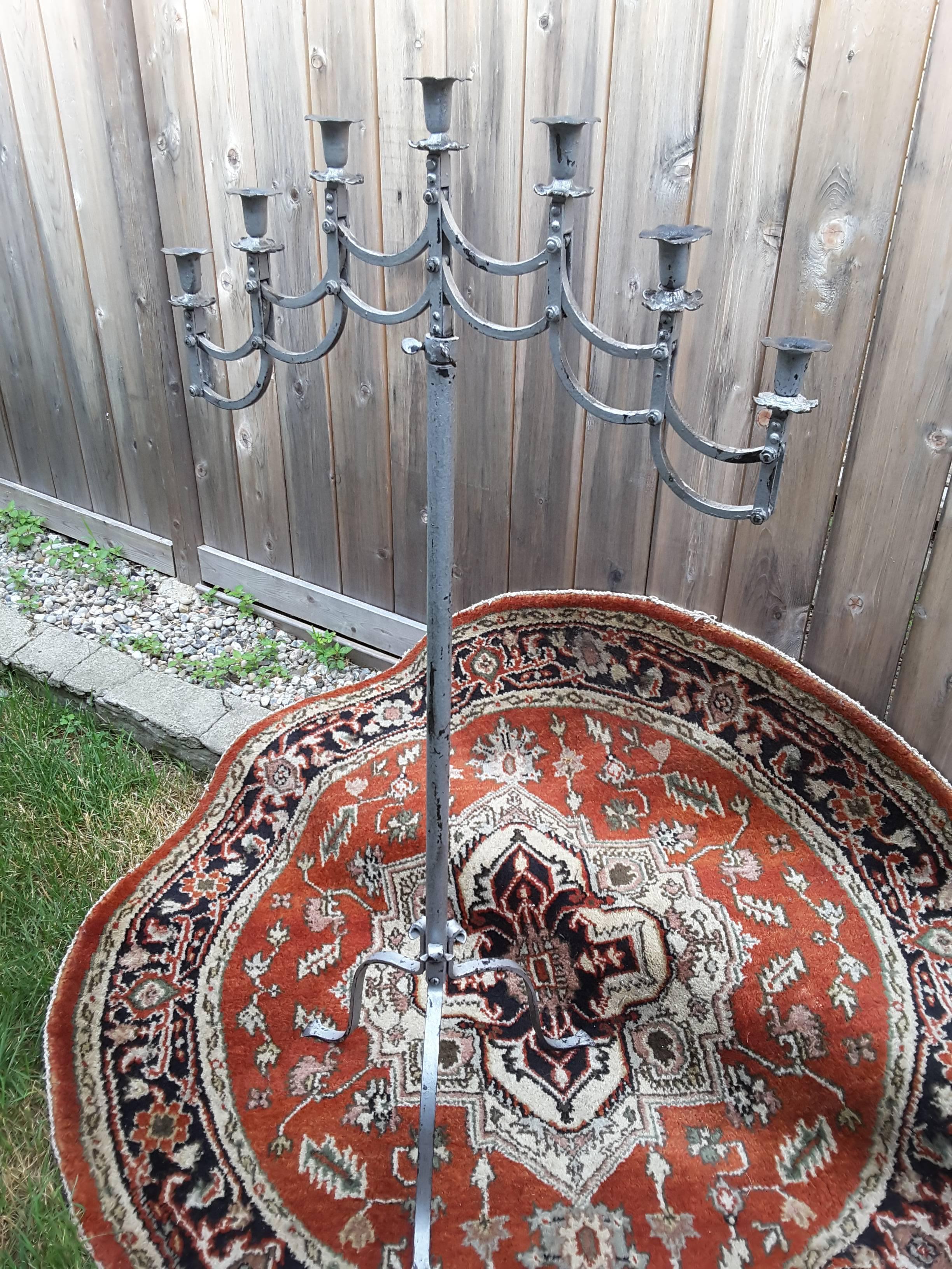 Wrought iron candelabra with adjustable height and articulated seven-arm candle holder, with tulip floral shaped drip cups, on a cabriole style leg and rolled top on center post the candelabra adjusts from center post, the arms move to any position