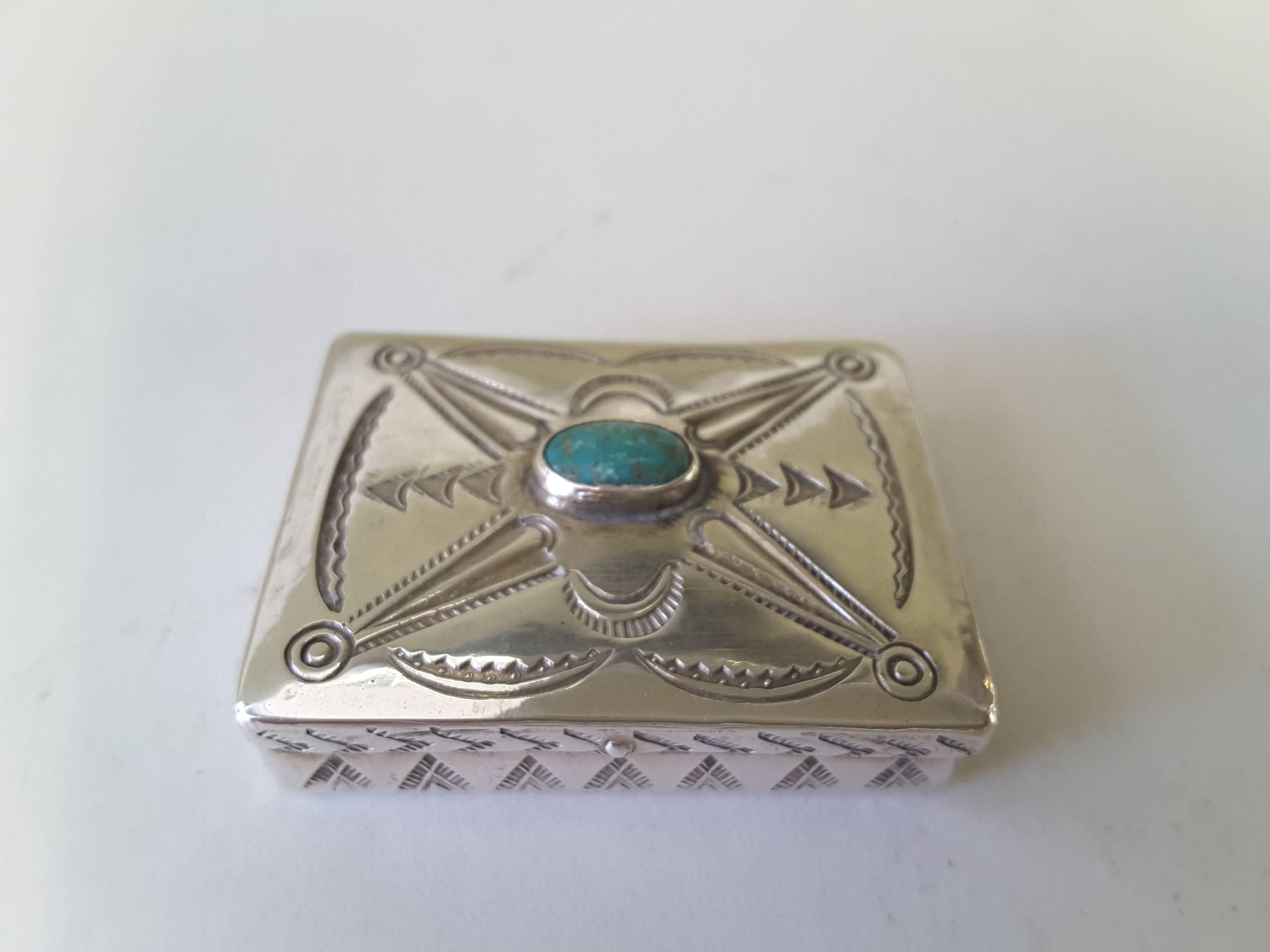 Miniature .925 Silver Navajo and turquoise trinket box, typical Navajo engraved design on five sides. The box has a turquoise stone mounted in the center on the lid. The box measures 1 5/8"-inches wide x 1 3/8"-inches deep x