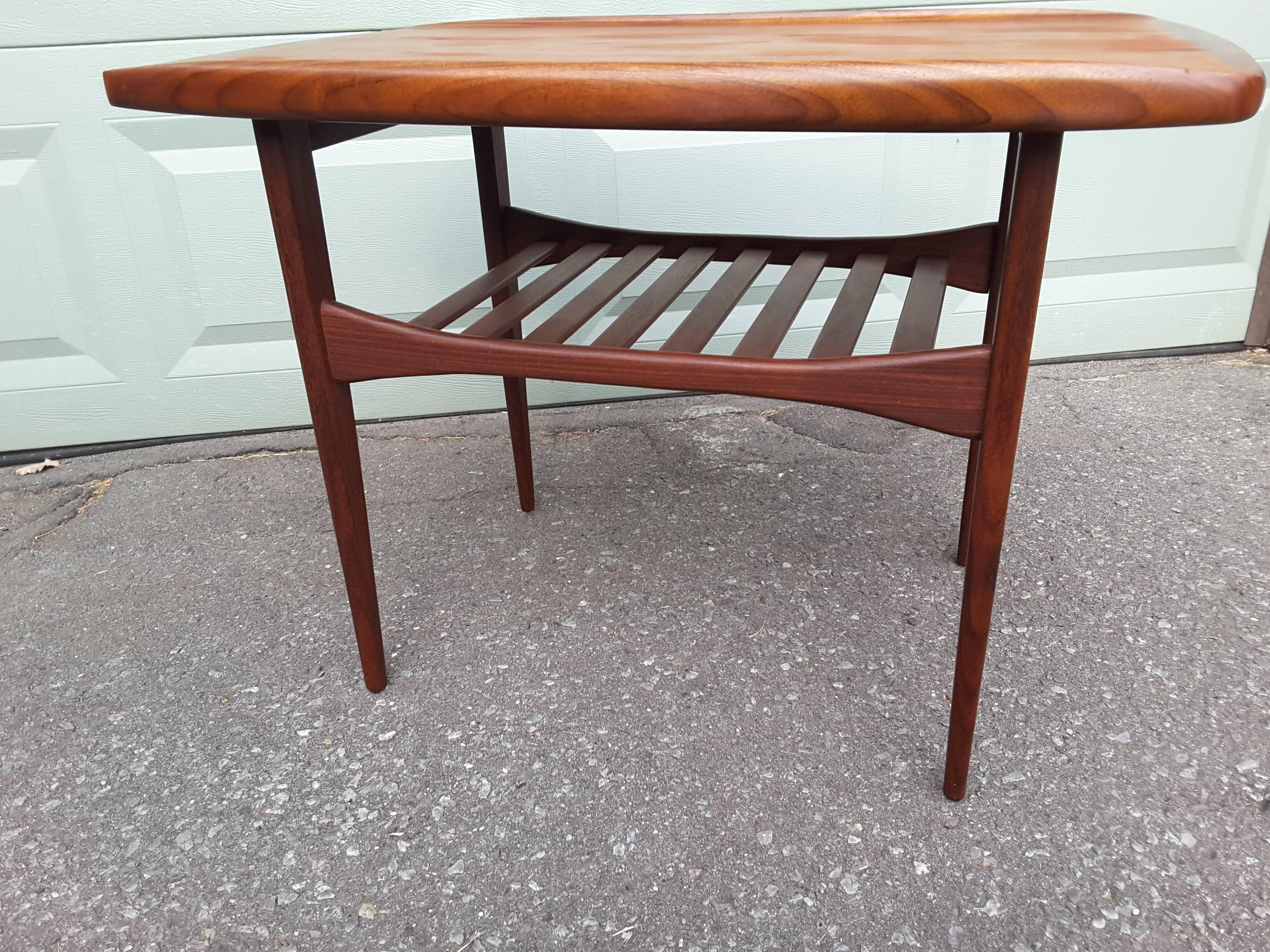 Kip Stewart end table in teak with rolled edge and lower slat shelf, lower shelf has a bow tie shaped side stretcher, a nice detail. The table measures 30