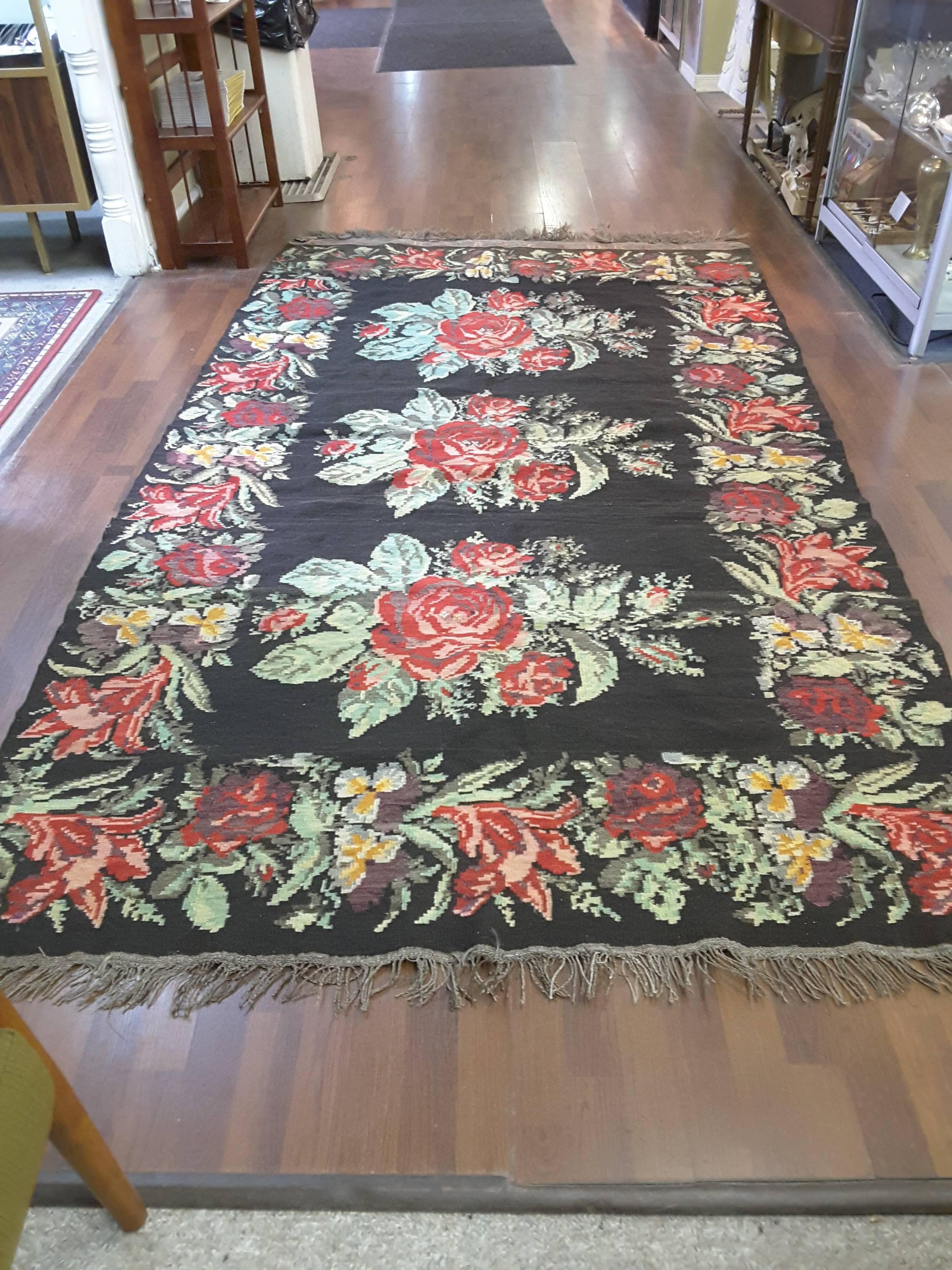 An antique Bessarabian Kilim carpet, floral patterns made in a naturalistic Western style on a black background, inscribed with the weaver's name and dated. In excellent condition, made in Romania, circa 1900. The size is approximately 114