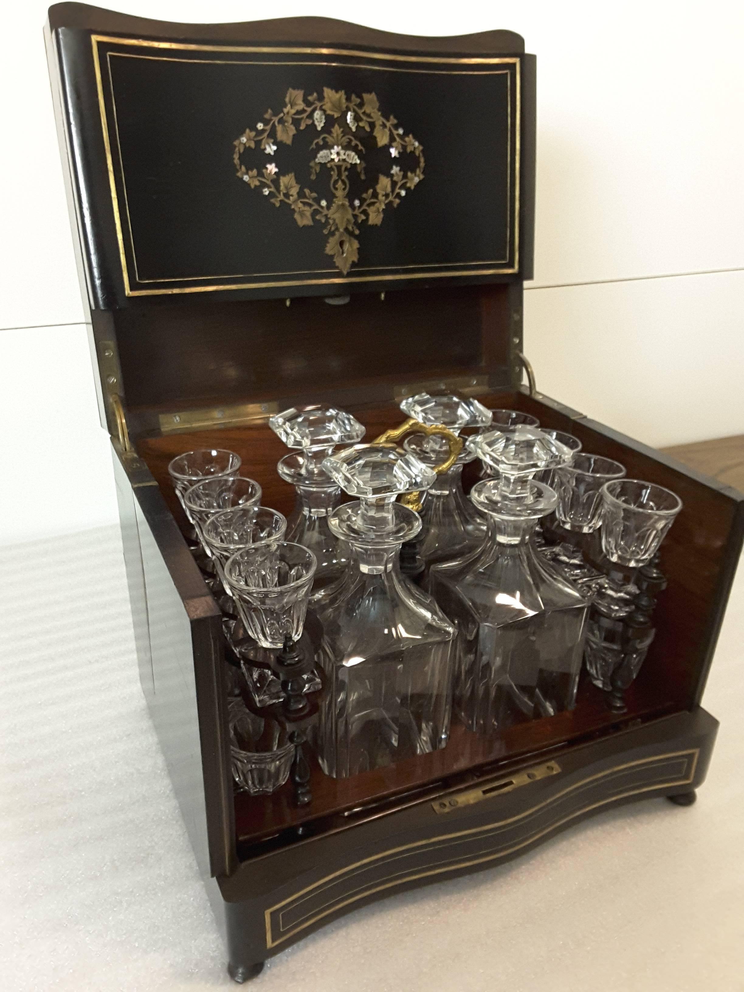 A fine 19th century, French, Napoleon III complete cave à liqueur / tantalus / liqueur / decanter set in cabinet. The set consists of 4 decanters and 16 glasses in a removable rosewood and brass insert. The case is done in ebonized mahogany,