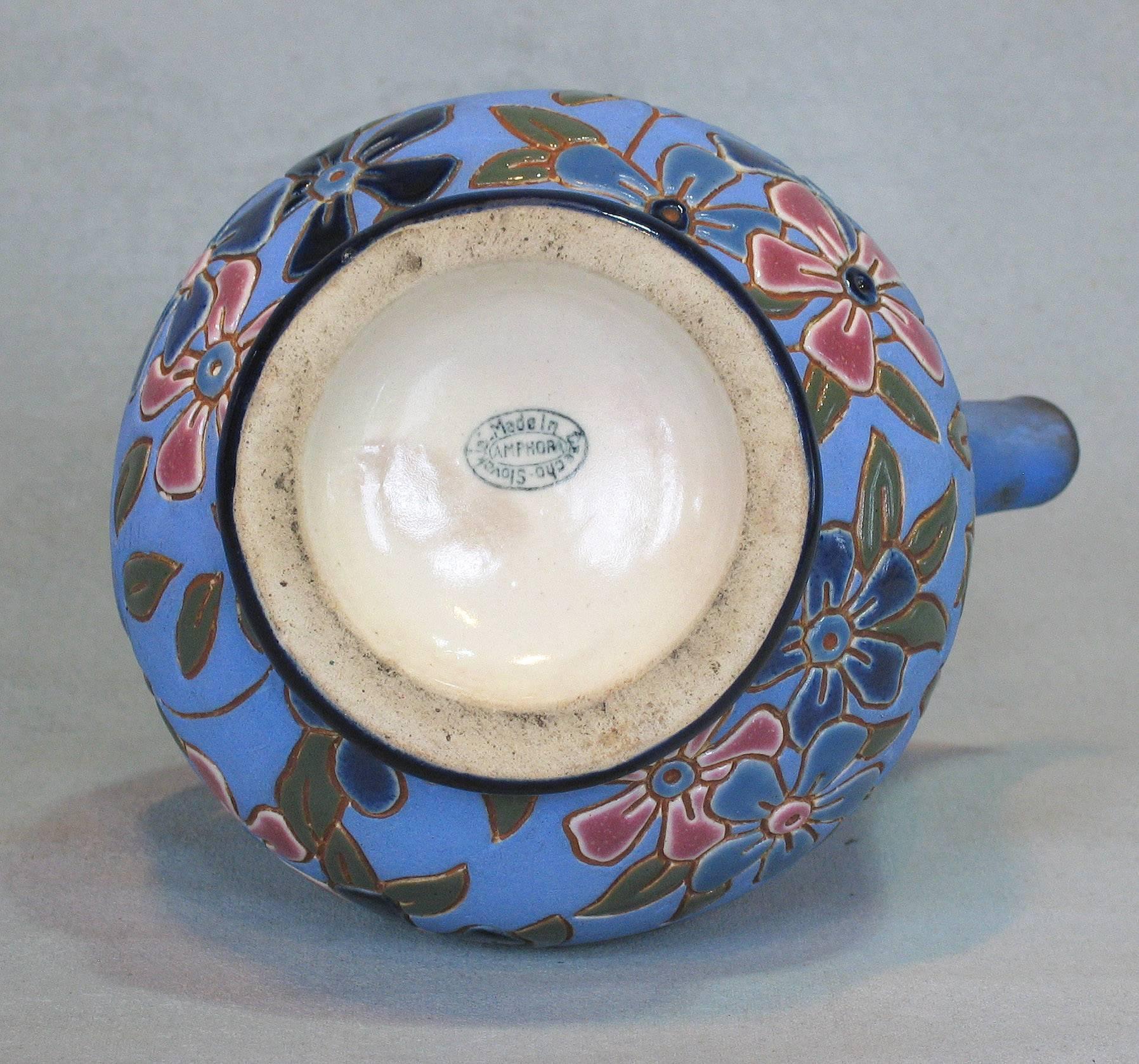 A Czechoslovakian glazed earthenware pitcher by Amphora, circa 1918-1939, incised enameled pottery blue background and floral stylized decorated. Opposite curve handle and spout, the pitcher is 8