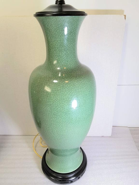 A pair of Celadon table lamps on Asian style black bases, the lamp porcelain is in a crisp apple green with new wiring and plugs, and original pull chain sockets. The Celadon lamps are in a Baluster shape mounted on Asian black bases with black caps
