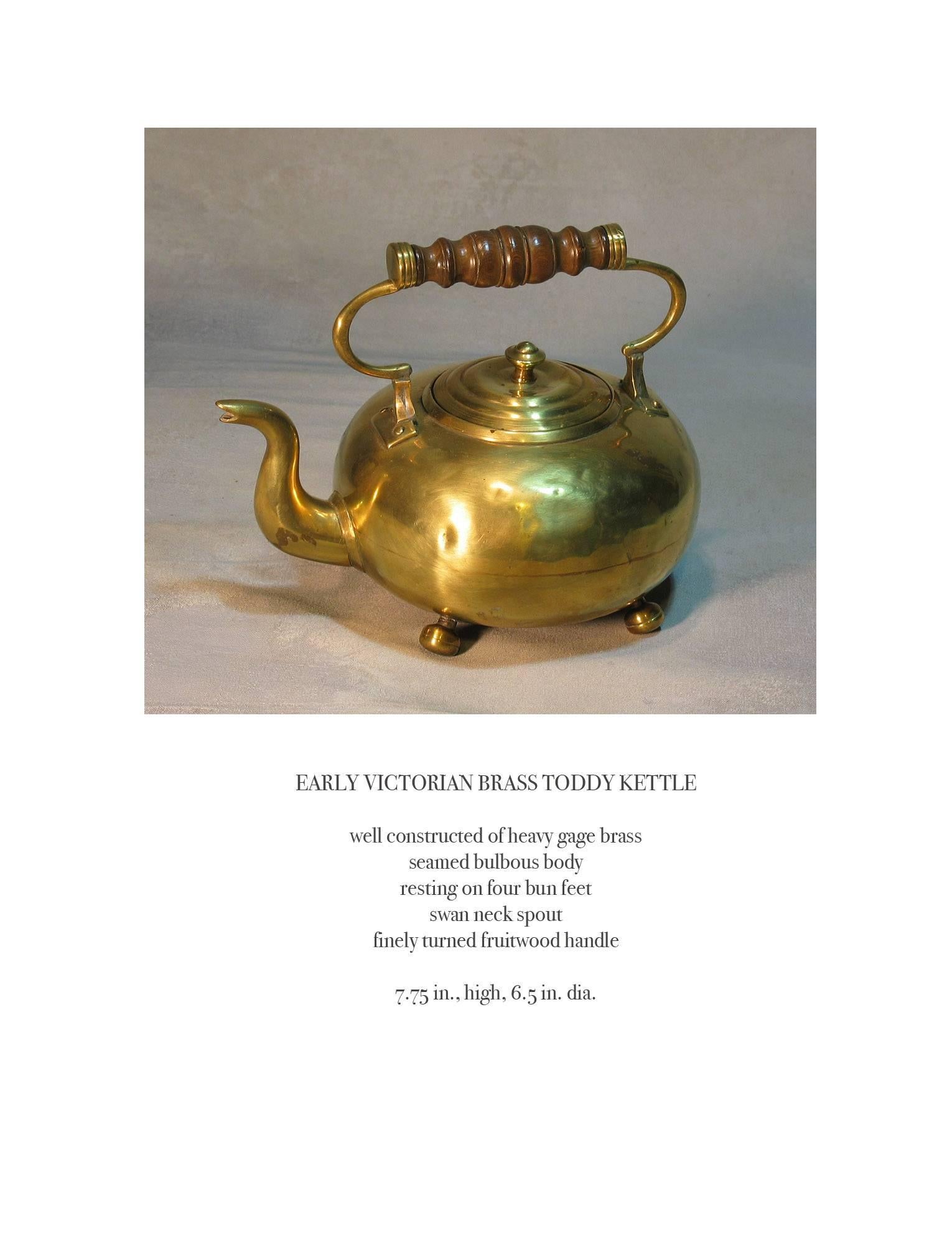 Early Victorian brass toddy kettle, fruitwood handle, circa 1840. Well-constructed of heavy gauge brass, seamed bulbous body resting on four bun feet, swan neck spout, finely turned fruitwood handle. The toddy measures 7 3/4