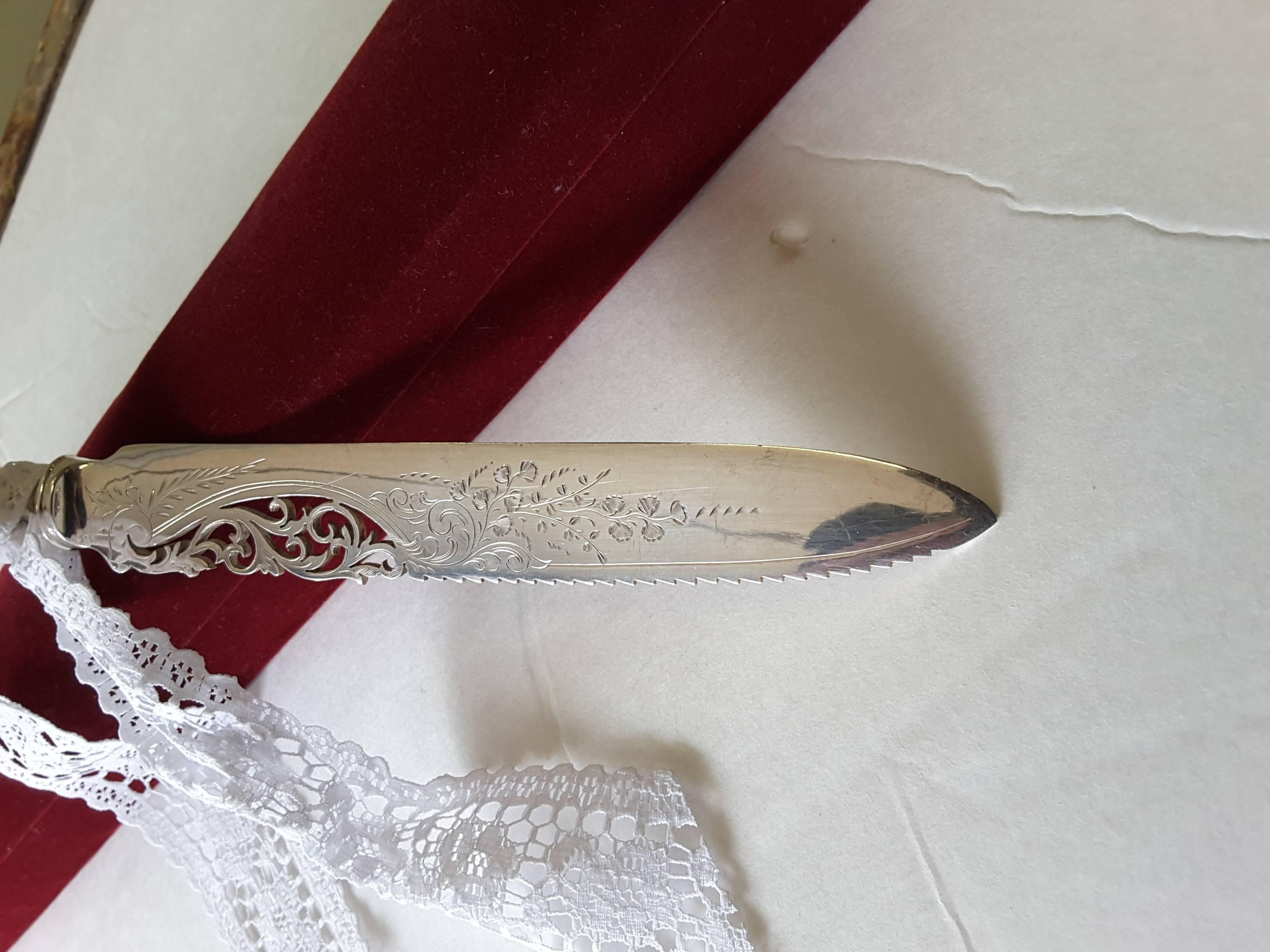 Bridal wedding cake ceremony sterling silver cutting knife, pierced decorated knife blade and decorated handle. The blade is decorated with a floral motif and serrated blade. The handle is marked Sterling, Birks (maker). The knife is 11