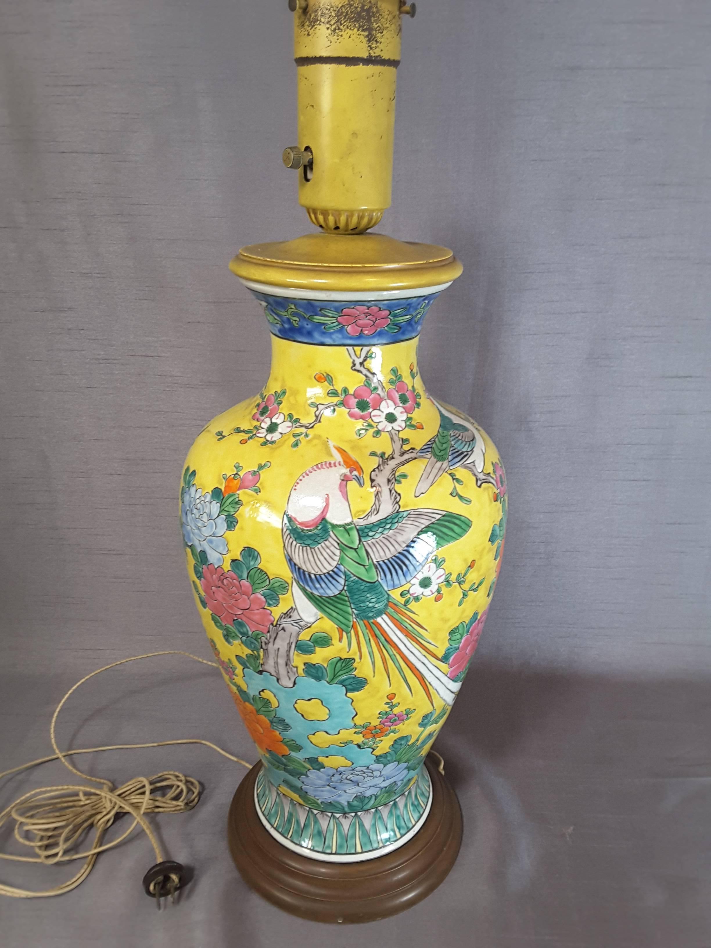 Chinese Imperial yellow large table lamp with pheasant, birds, flowers and foliage. Baluster shaped vase mounted for a lamp. The lamp is done in ceramic, decorated in bright vibrant colors and glazed, mounted on a wood base, top yellow cap with