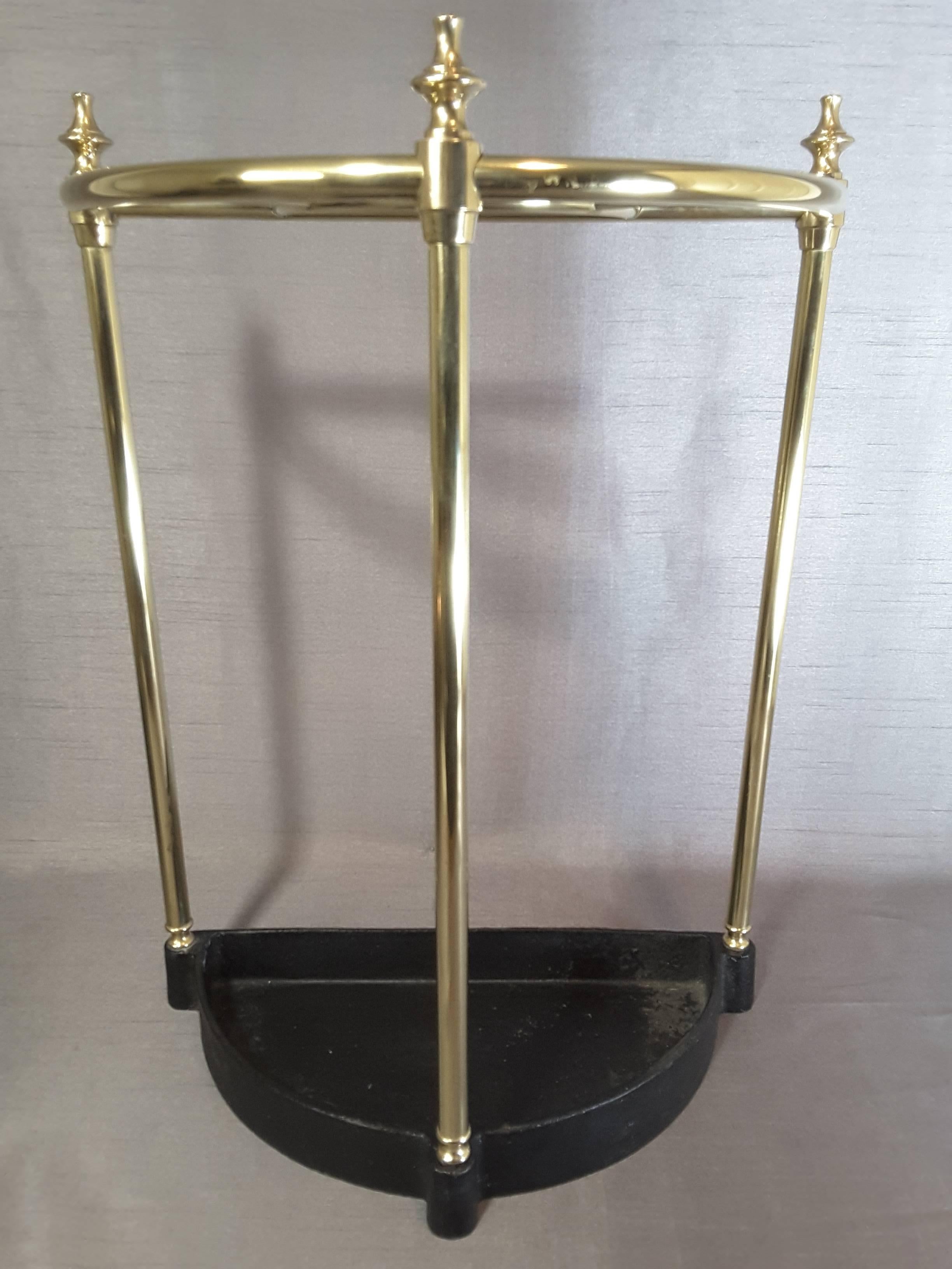 Edwardian brass and cast iron cane & umbrella stand, with a section top for separation of canes and umbrellas. The base is cast iron with a raised edge to catch water dripping. The brass is slightly flared for a visual look, with a turned finial