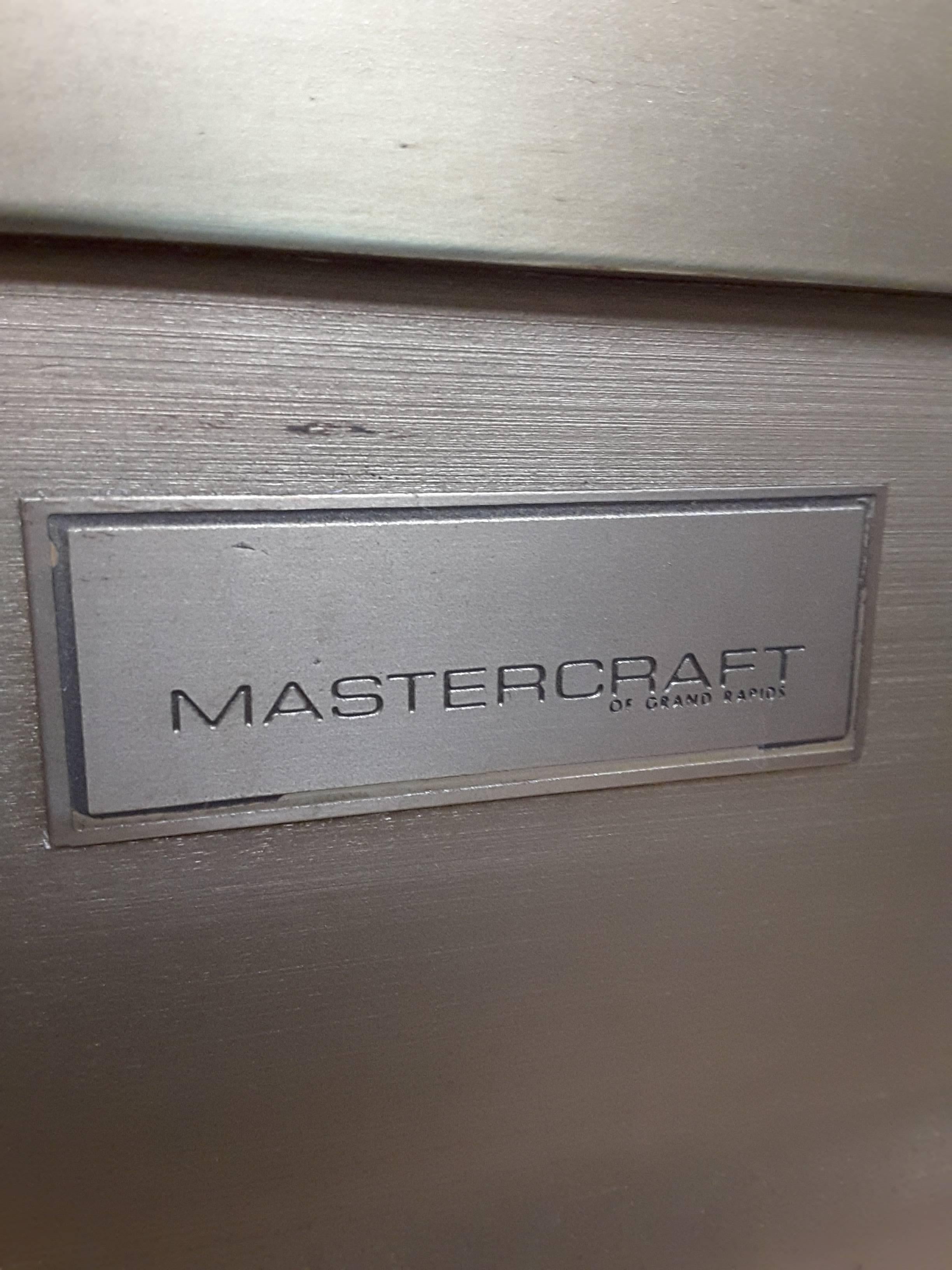 Exceptionnel buffet Mastercraft en laiton, stratifié et verre, comprenant deux portes inférieures avec de grandes poignées en laiton ouvrant sur une étagère inférieure et une étagère centrale. Au-dessus des portes se trouve un long tiroir unique