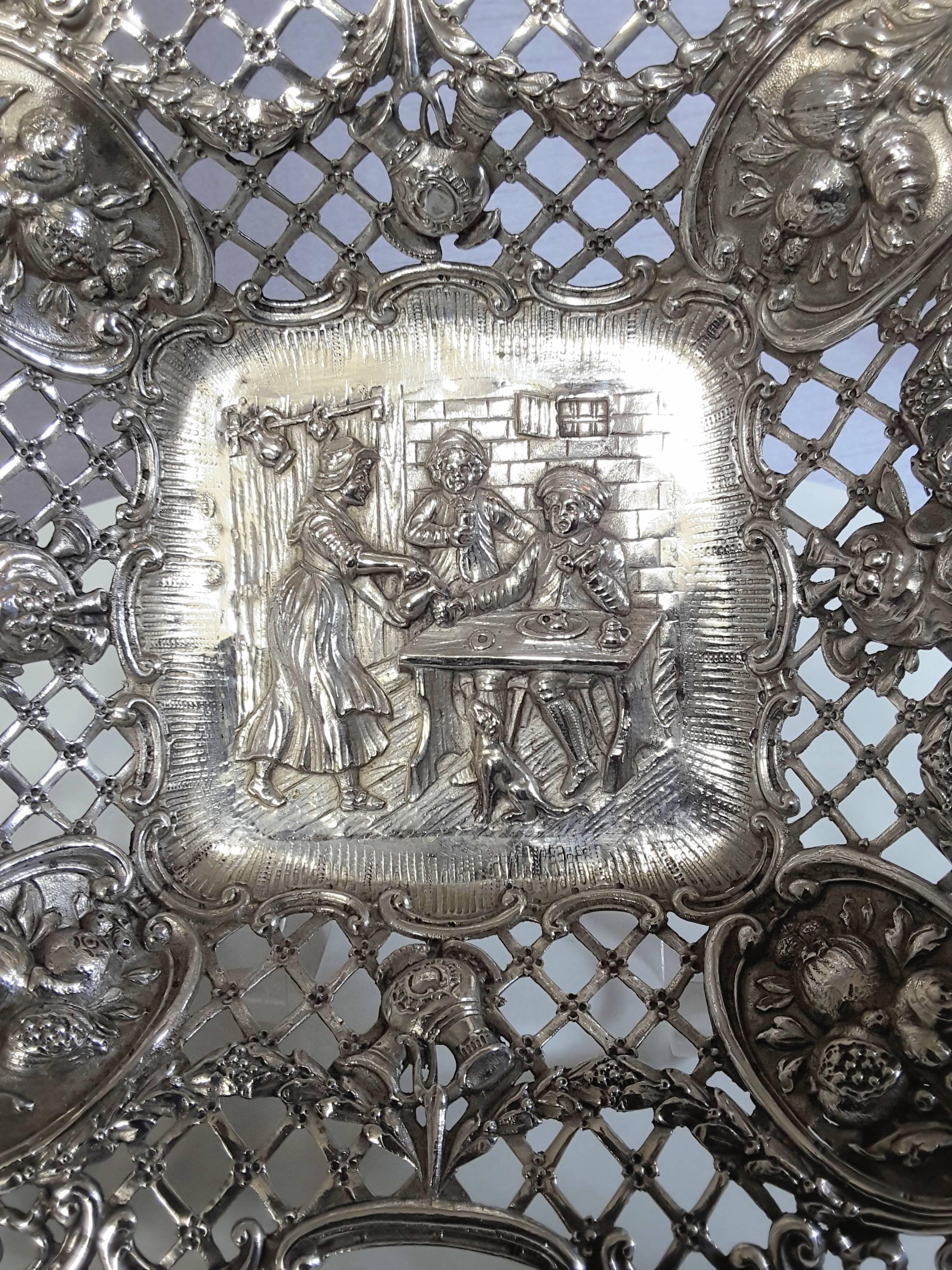 Dutch scene sterling silver pierced bowl, Hanau, Germany, makers mark GR in a heart cartouche, for George Roth, 1891-1919, The dish is scalloped shaped around the sides pierced and decorated with scrolls, vines, horns and four fruit bearing branches