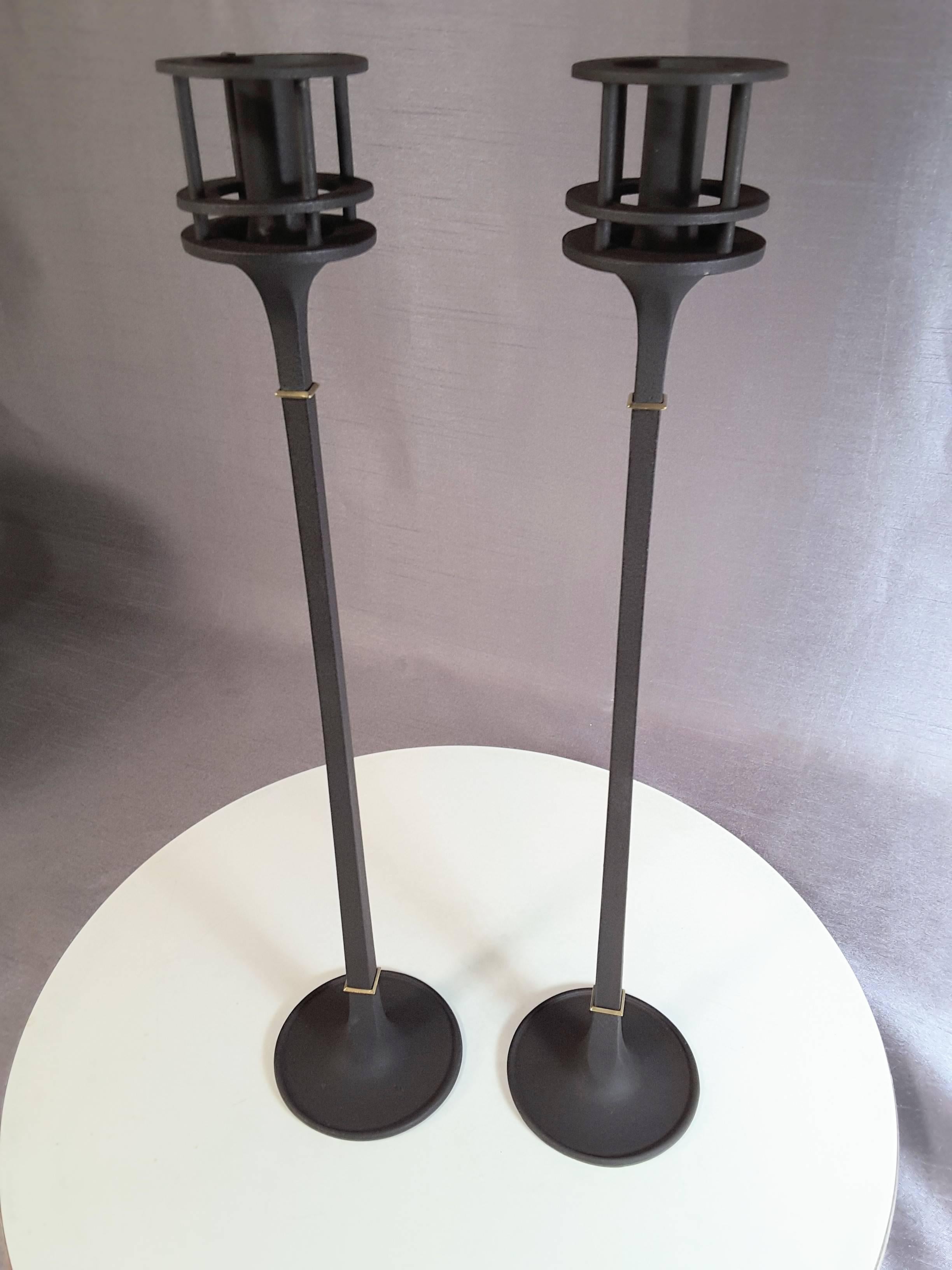 Dansk Designs 1960s iron candlesticks by Jens Quistgaard, this Classic tall pair of elegant Mid-Century Modern iron candlesticks are accented by two brass collars on a square shaft. The were designed by Jens Harald Quistgaard for Dansk and Dansk