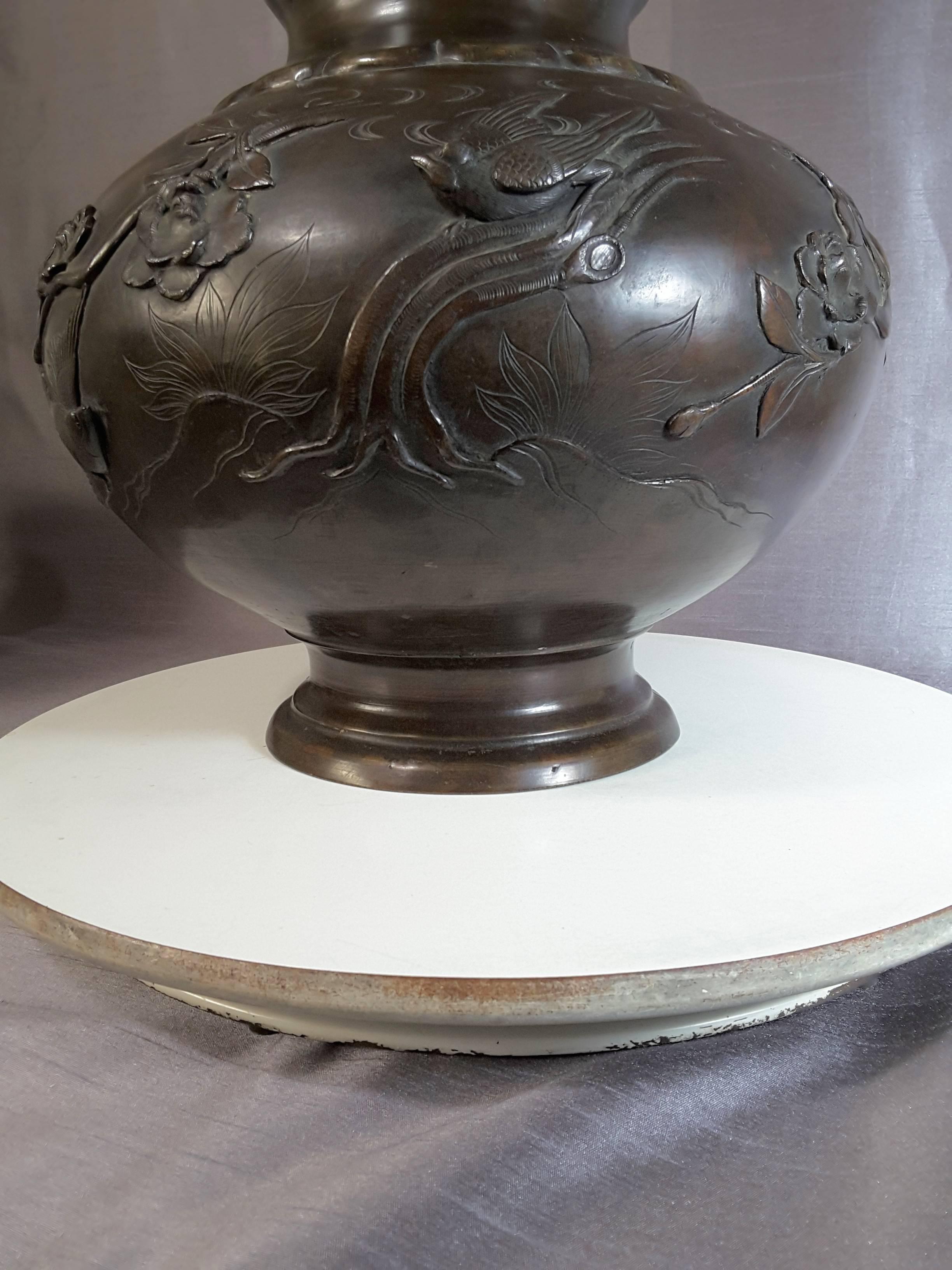 Meiji period Japanese bronze vase with raised birds, branches and foliage, the vase is in a bulbous shape on a raised circular base. The birds are raised/embossed and have a space behind the head for a realistic profile. The branches and flowers are