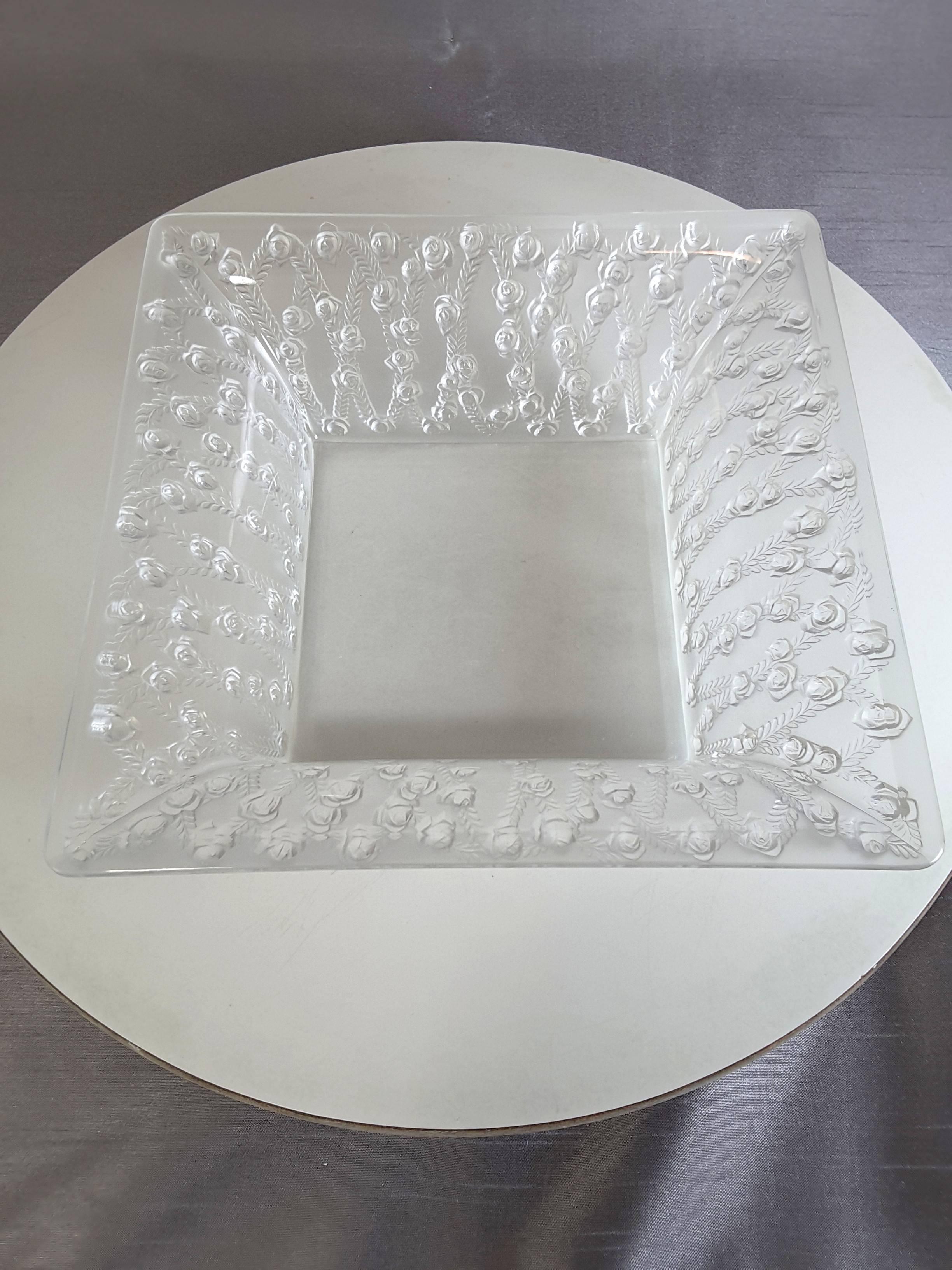Lalique clear crystal roses bowl, designed in 1939, the square bowl has a multitude of open roses with vines intertwining, coming up on a flared base to top. The bowl is wheel cut signed Lalique, France on the bottom. 
The bowl measures 9