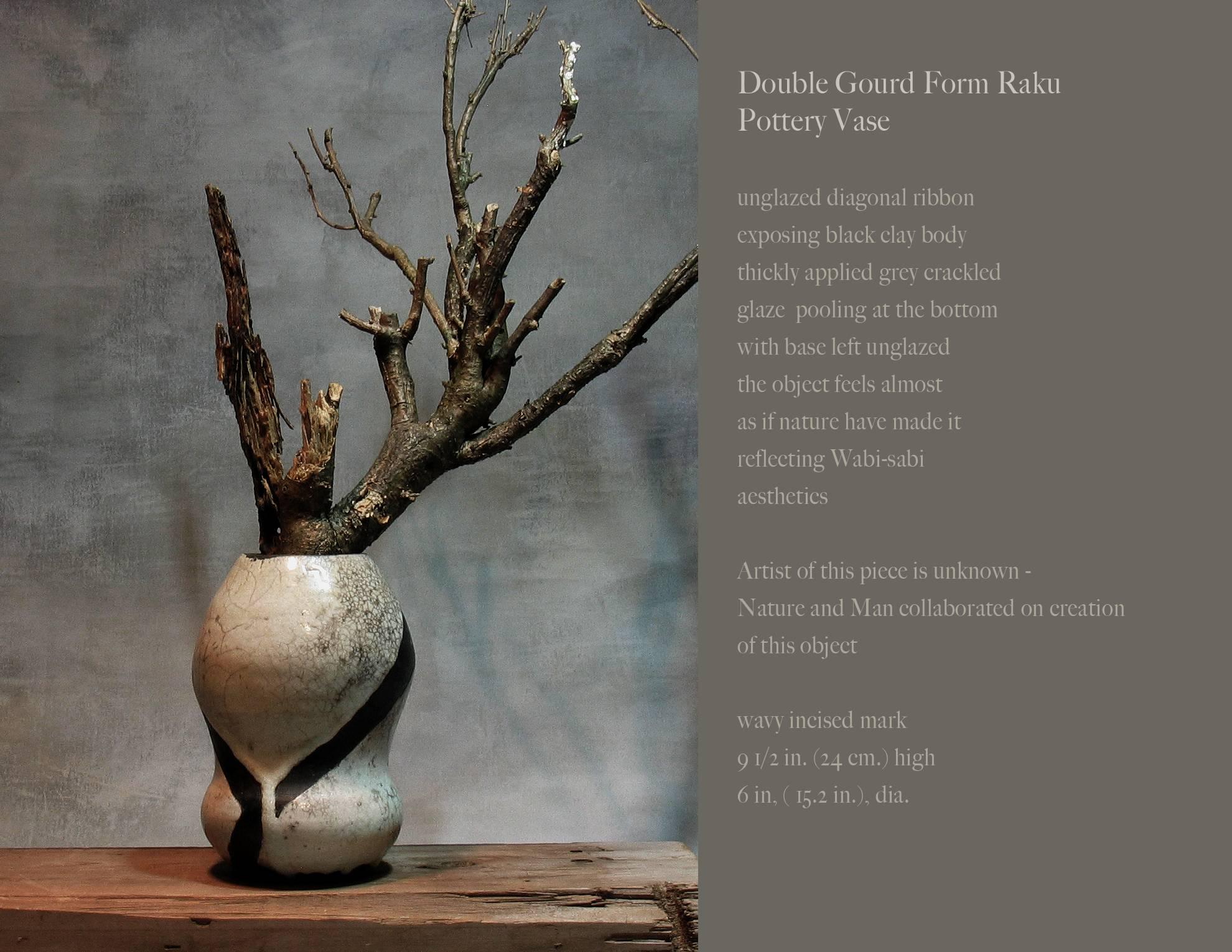 Artistic Double Gourd form Raku pottery vase, unglazed diagonal ribbon exposing black clay body thickly applied grey crackled glaze pooling at the bottom with base left unglazed the object feels almost as if nature have made it reflecting Wabi-Sabi
