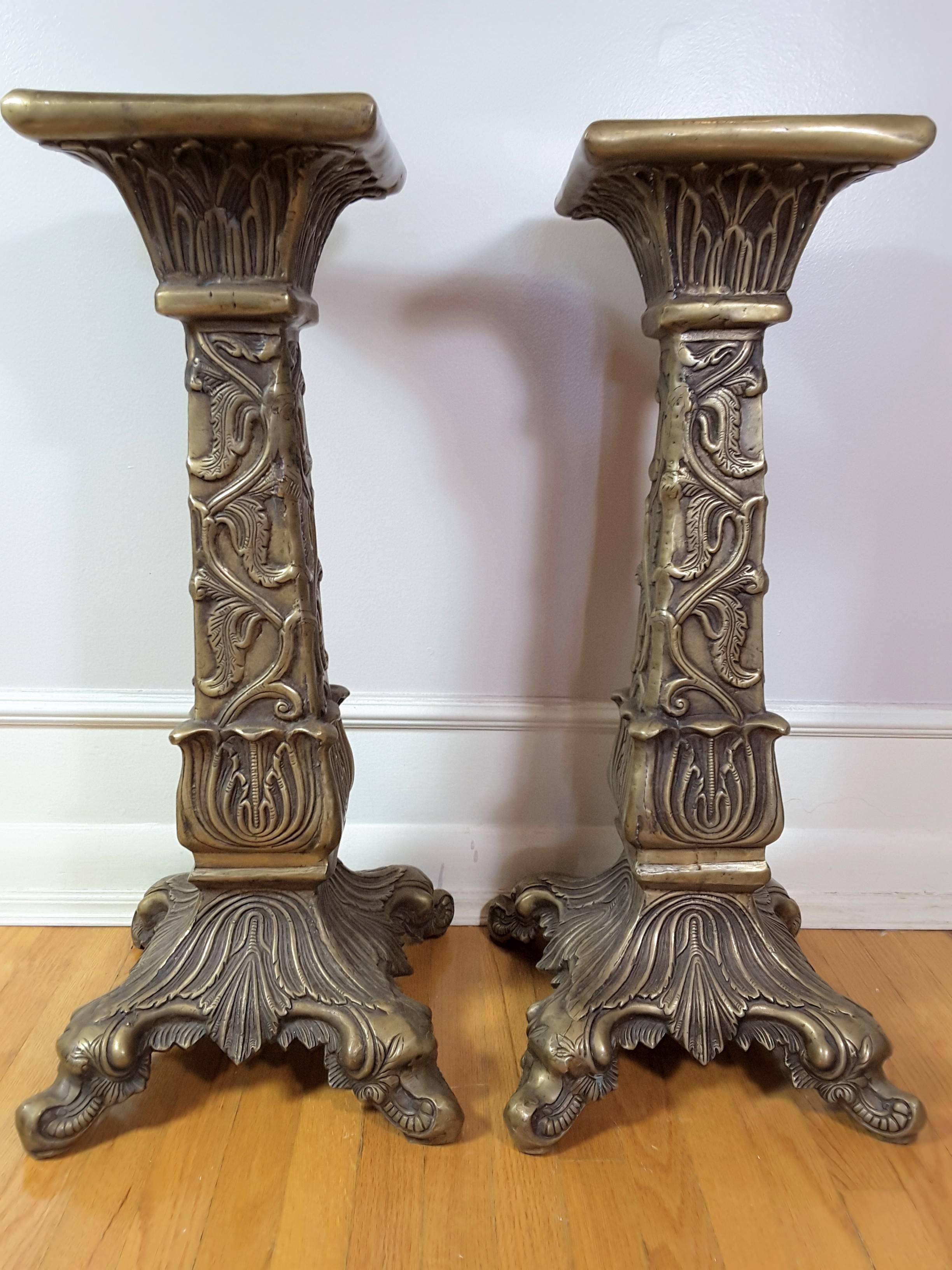 Pair of Mid-Century Modern solid brass patinated pedestals, The pedastals are done in a leaf and vine pattern on the columns, Raised scroll feet, Flaired to a square flat top. The pedastals are from the mid-1960s-1970. The stands measure 26