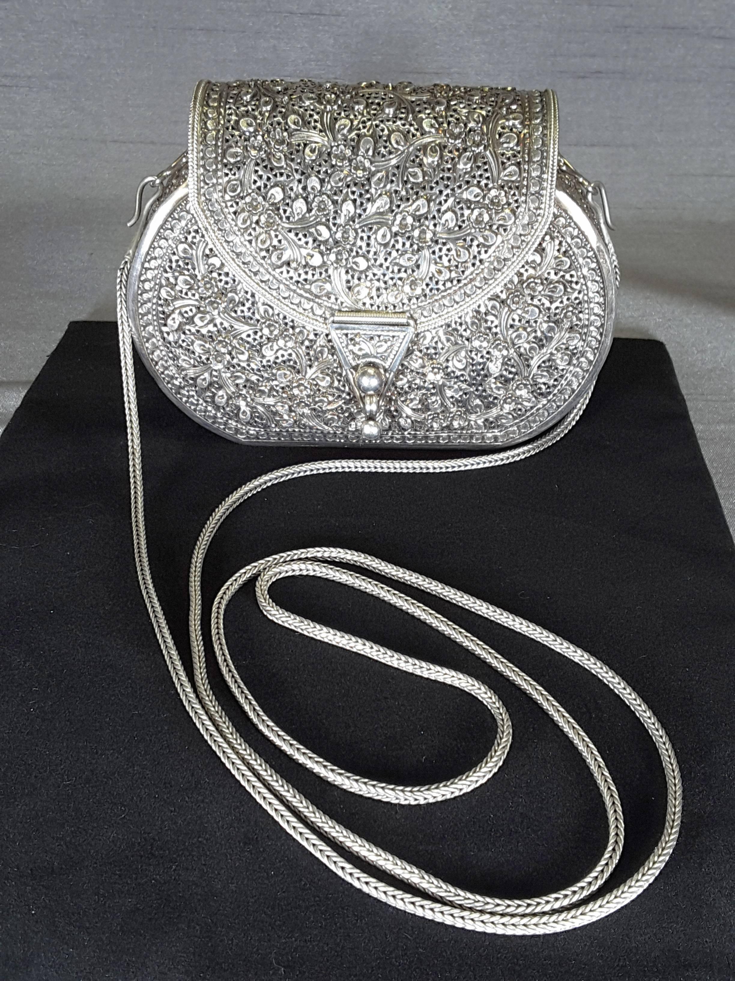 Sterling silver floral decorated evening purse with long braided silver chain, made entirely of silver with a rounded fold over top and closure. The purse is stamped .925 on the front under the top. The rounded purse/evening bag/clutch purse is
