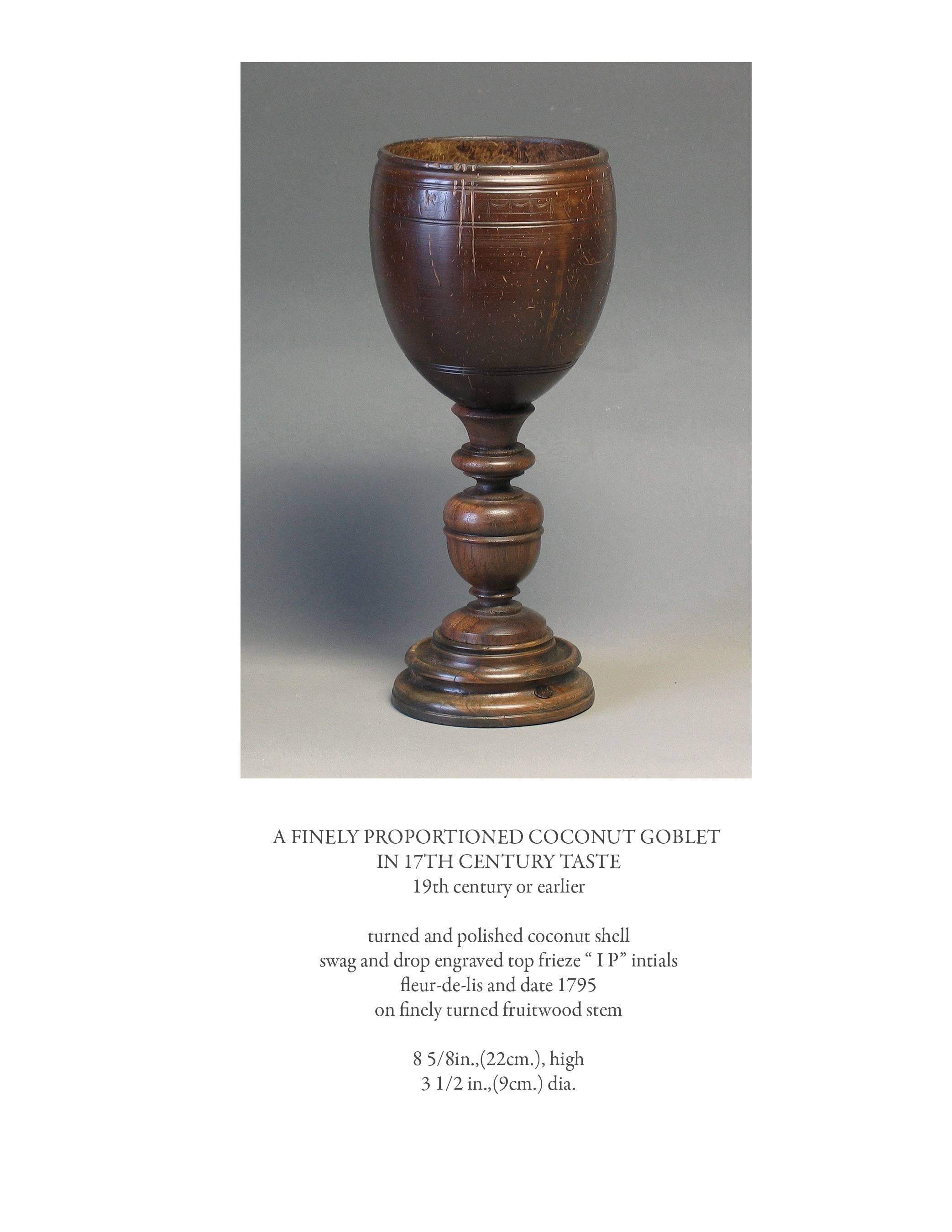 A finely proportioned coconut goblet in 17th century taste, 19th century or earlier, turned and polished coconut shell, swag and drop engraved top frieze, "IP" initials, fleur-de-lis and dated 1795, on a finely turned fruitwood stem. The