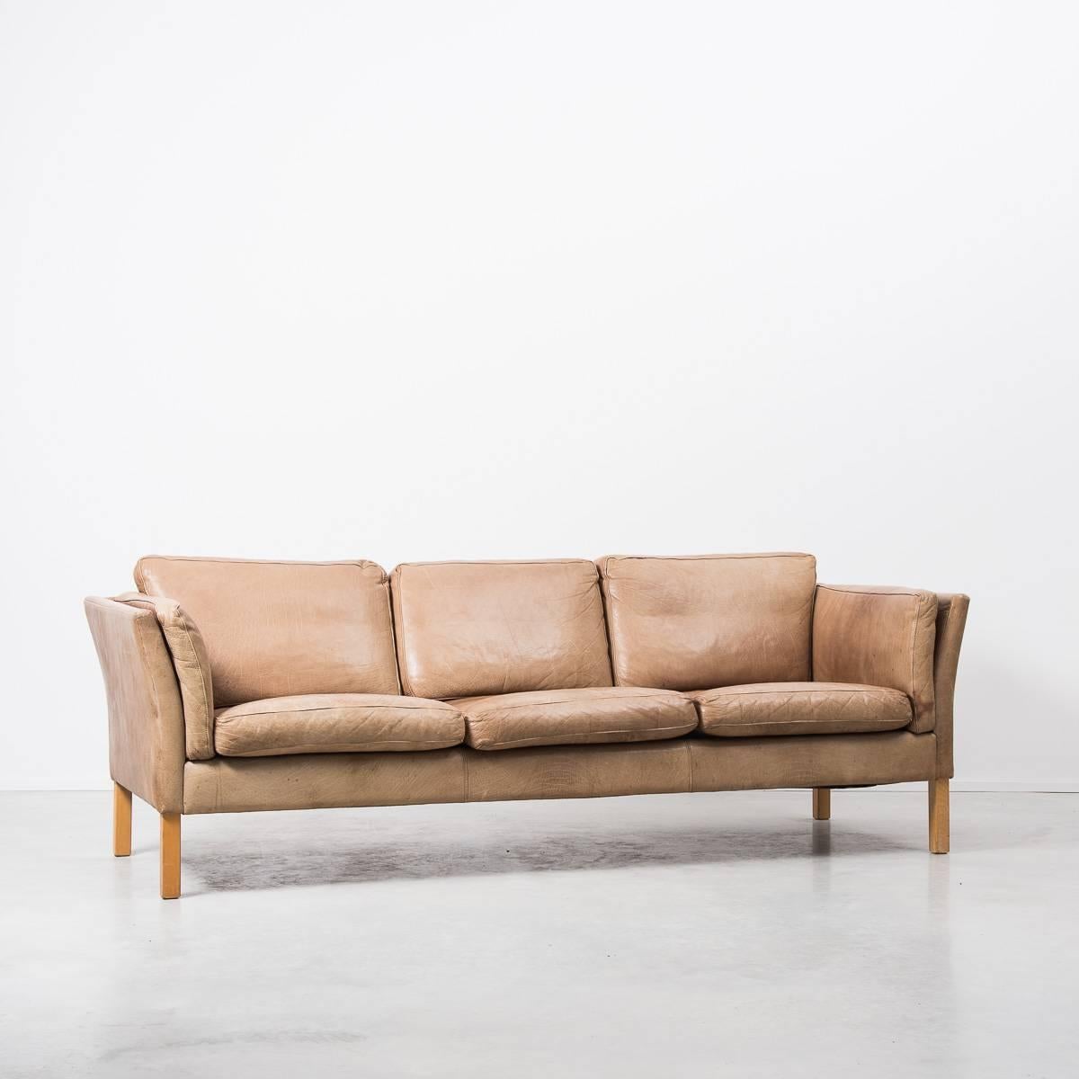 Beautiful quality Erik Jorgensen Danish leather three seater sofa, manufactured in the 1950s Denmark. Faded to a light buttery tan colour, the sofa is in good vintage condition with a desirable amount of patina and age to the leather. It has the