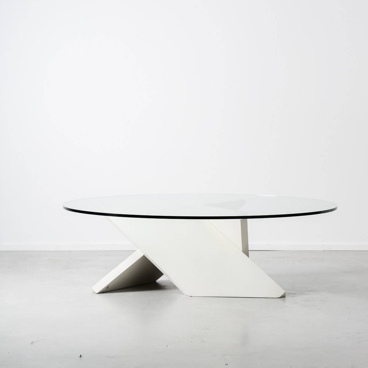 Glass round coffee table with heavy white geometric base. Postmodern era, sturdy construction in thick plate glass. Style reminiscent of Memphis and De Stijl schools of design.
 