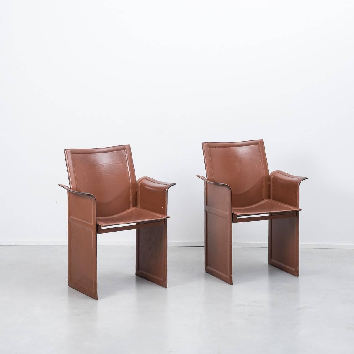 A pair of leather Korium chairs from Italian designer, Tito Agnoli for Matteo Grassi in the late 1970s, in rich rust / burgundy colour.

The chairs feature stitched and moulded leather on metal frame panels. Two are in excellent condition with