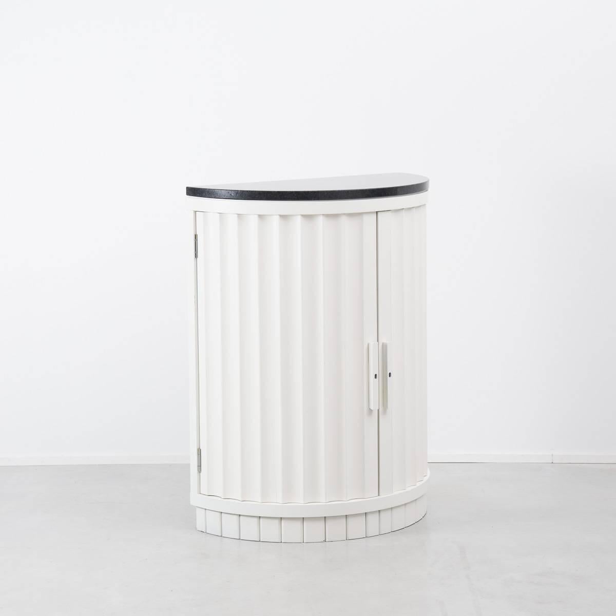 This is an old edition of a demilune drinks cabinet by Ralph Lauren Home, from their Penthouse range. The cabinet’s fluted exterior mimics an aesthetic detail most commonly associated with architectural columns. Internally, the cabinet has a simple