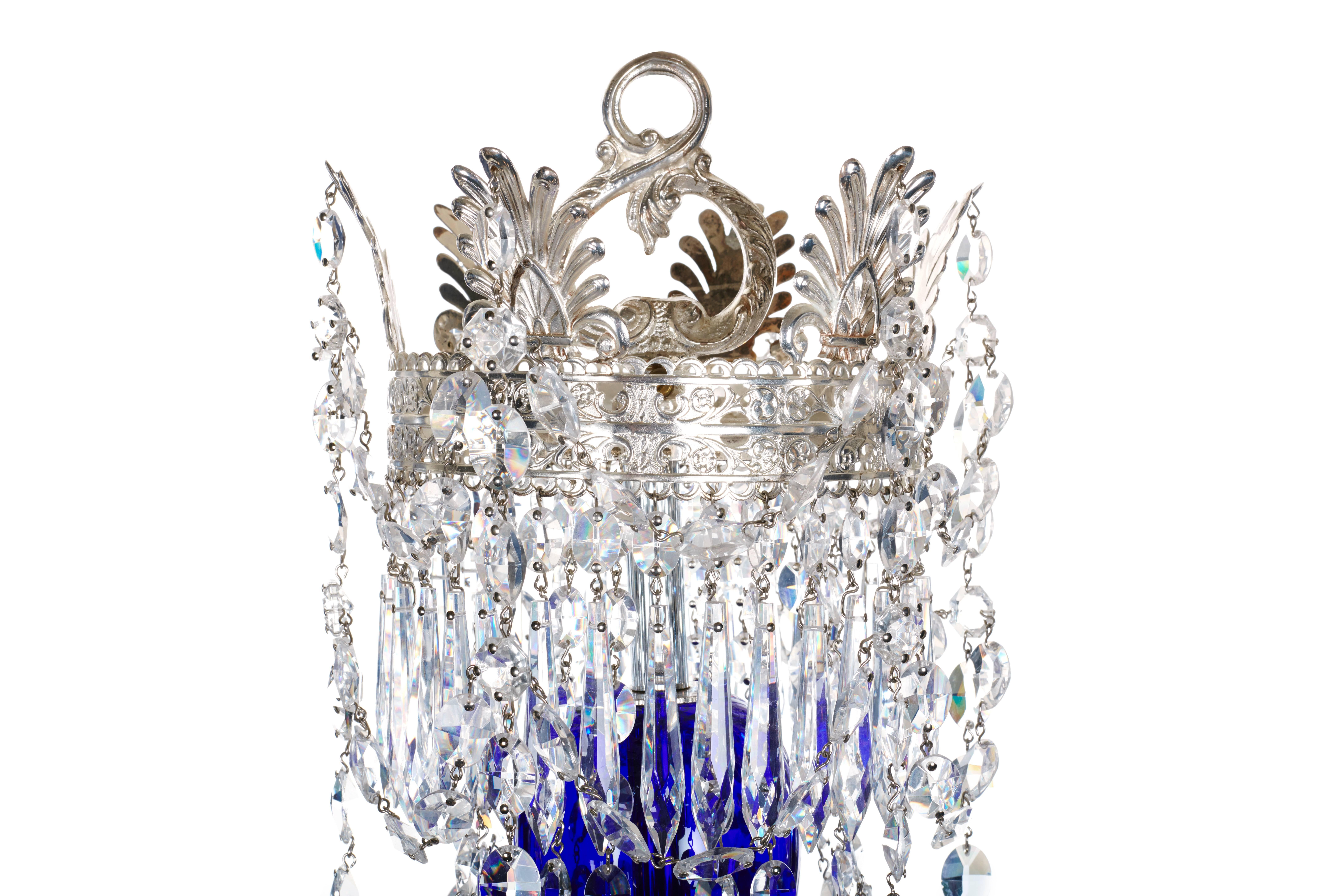 A Baltic silvered glass eight armed chandelier with a central baluster of cobalt blue. The large silver hoop within a cobalt blue flat plate with swags of oval faceted buttons form a central anthemion crown, with downwards swept chain of oval