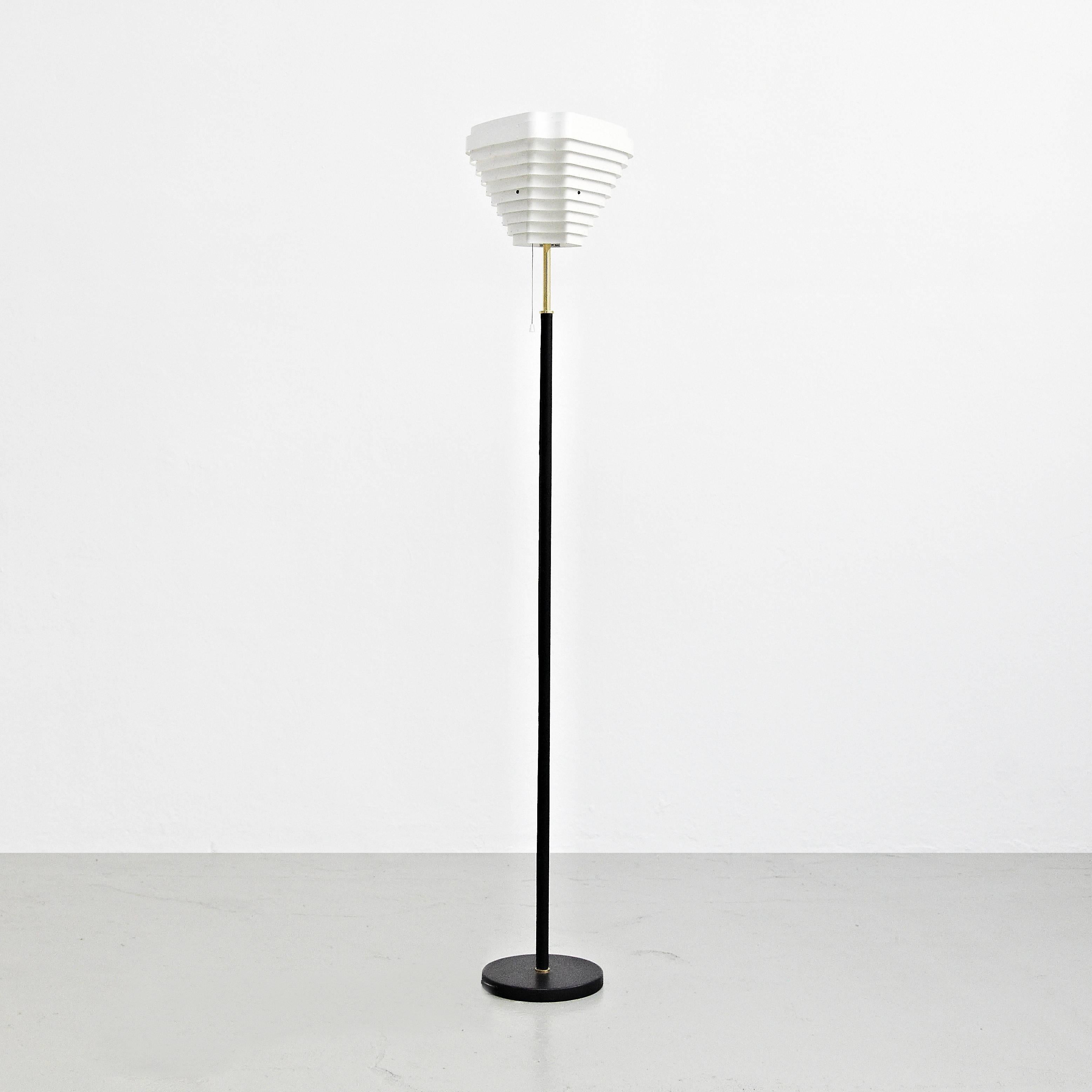 Floor lamp designed by Alvar Aalto manufactured in Finland by Artek, circa 1960.

White enameled metal, vented roughly conical shade on a black leather sleeved brass shaft.

In great original condition, with minor wear consistent with age and