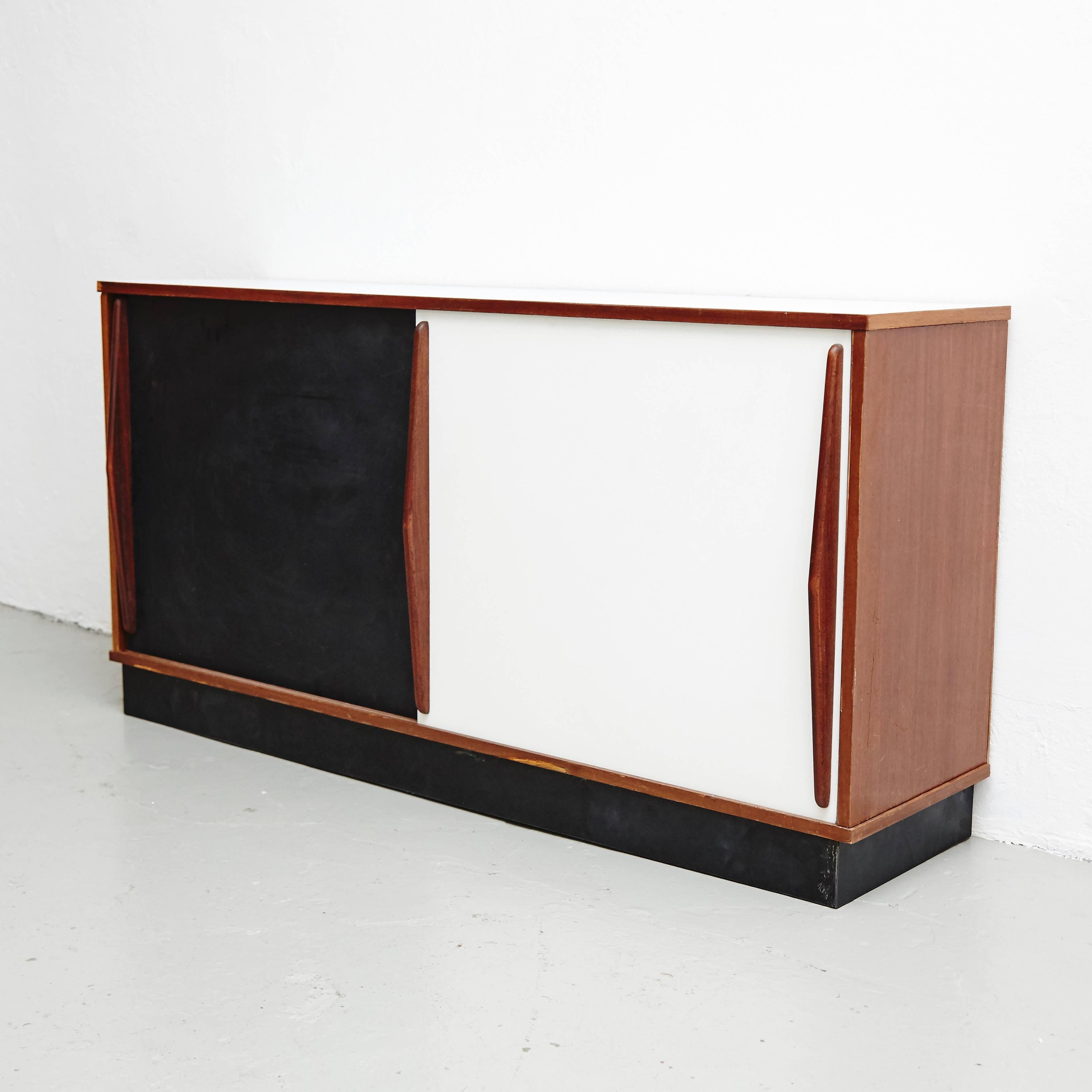 Sideboard designed by Charlotte Perriand, circa 1950.
Edited by Steph Simon (France.)
Wood structure and grips, lacquered sliding doors.

Provenence: Cansado, Mauritania (Africa.)

In good original condition, with minor wear consistent with
