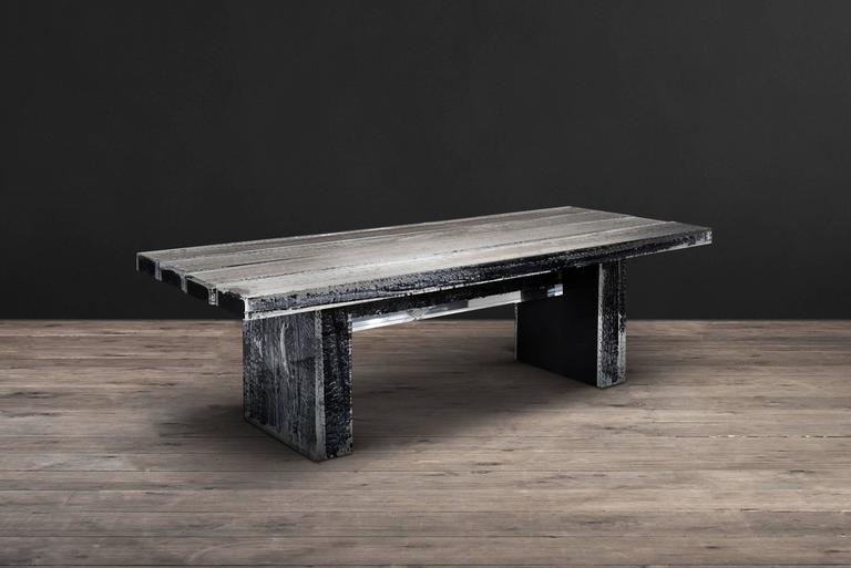 Table Ice Burnt with burnt timber in crystalline 
acrylic. Ice-cold smooth appearance contrasts with 
charred rugged timber. Table features four beams 
of timber encased in acrylic, set atop two large 
timbers also in acrylic. The bubbling