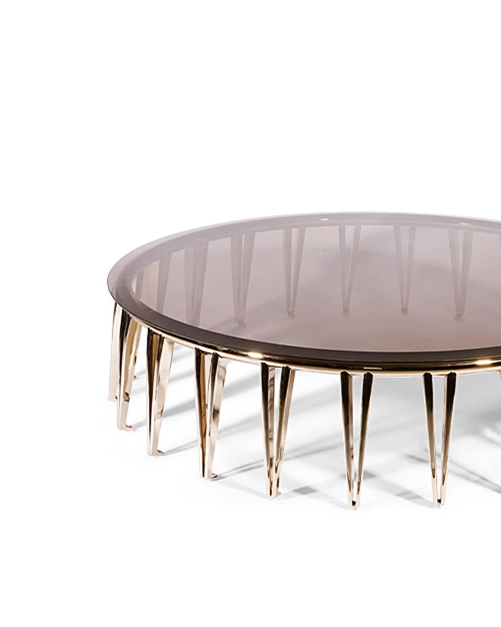 Table basse octopus avec structure en laiton avec 
pieds formés et surface en verre fumé avec anneau 
haut. Pièce subtile.
.
