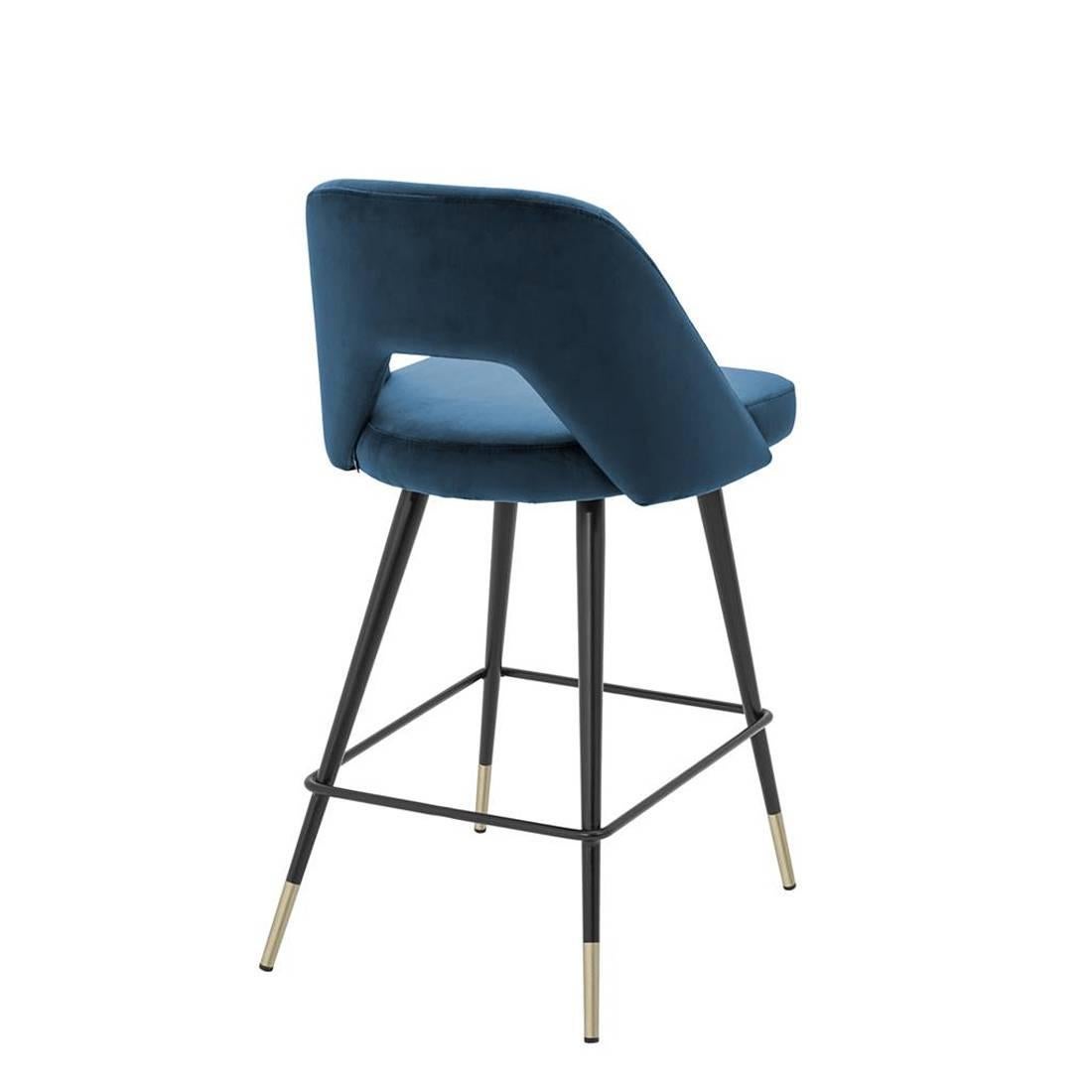 Bar Stool Perfecto Medium upholstered with blue velvet 
fabric with fire retardant treatment. Base structure in iron
in black finish with polished brass feet.
Also available upholstered with red or green velvet 
fabric. Also available in Bar Stool