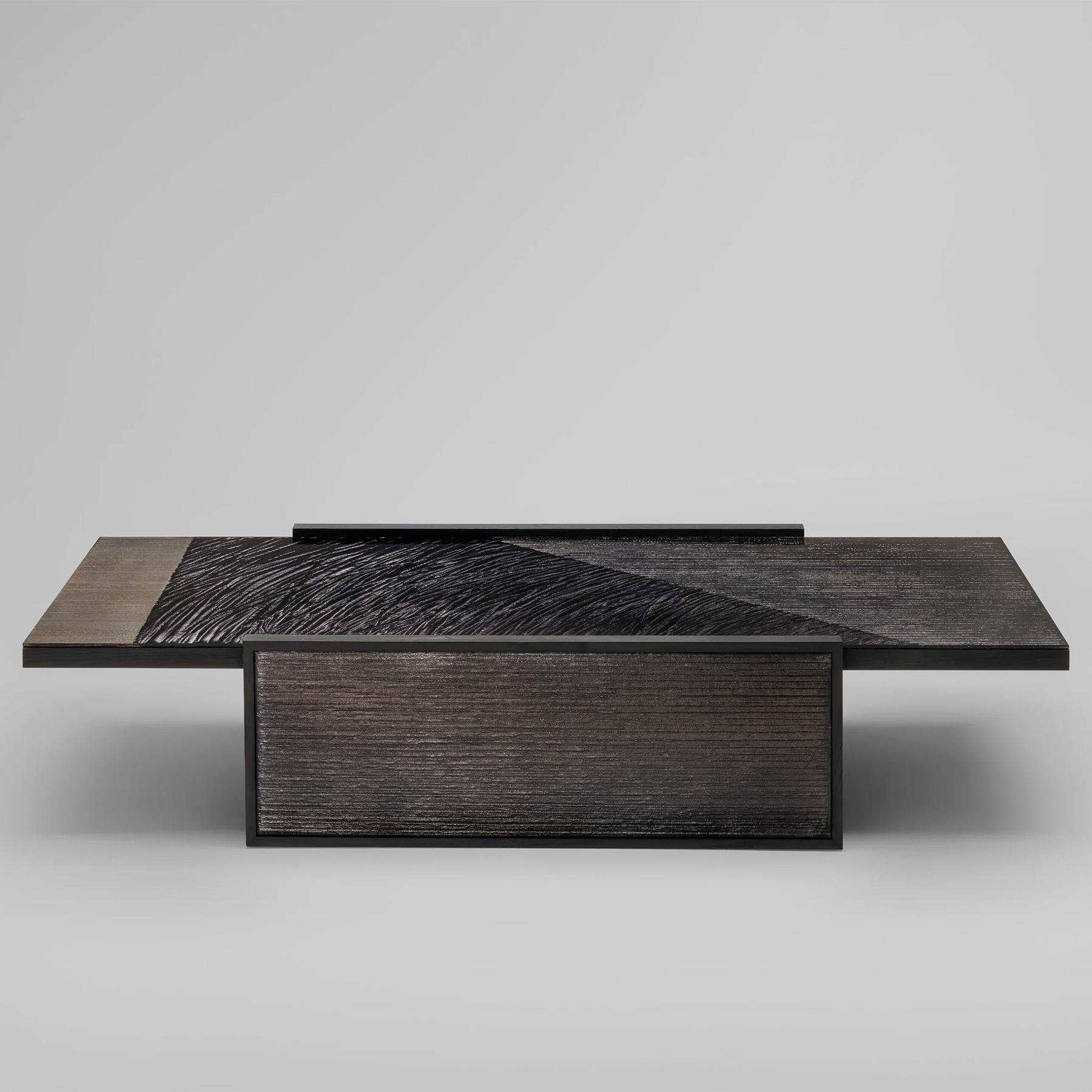 Mesa de centro de madera-cristal con estructura de bastidor de 
madera de fresno en chapa teñida de negro. Tablero y pata 
laterales recubiertos de cristal extraclaro con cristal grabado en 
sobrio acabado oscuro umbra.
